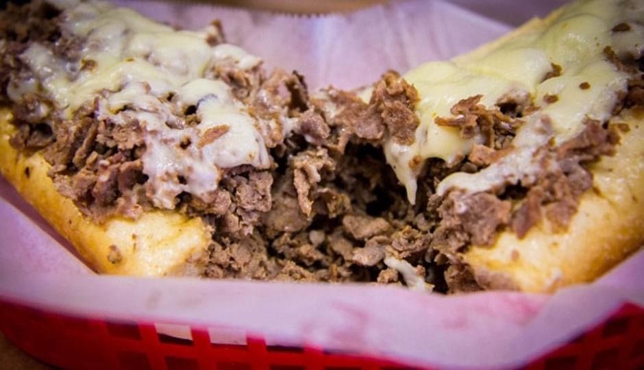 Cheesesteak sandwich with melted cheese on a bun in a red basket liner
