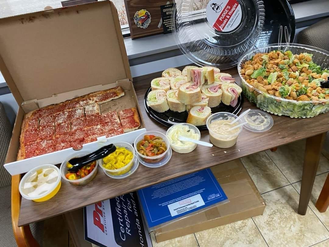 Table with assorted packaged foods, sandwiches, salads, and dips displayed on a buffet setup