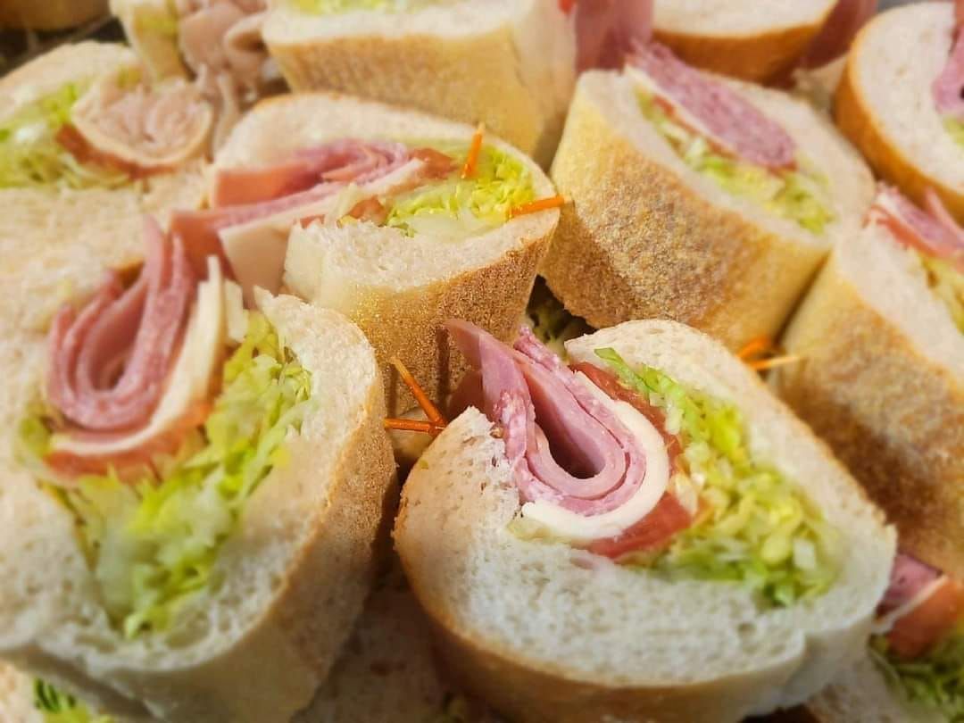 Assorted ham and lettuce finger sandwiches stacked on a platter