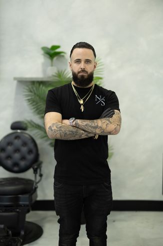 Professional barber posing inside a modern barbershop in Laval