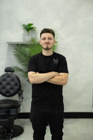 Barber posing inside a modern men's grooming salon in Laval