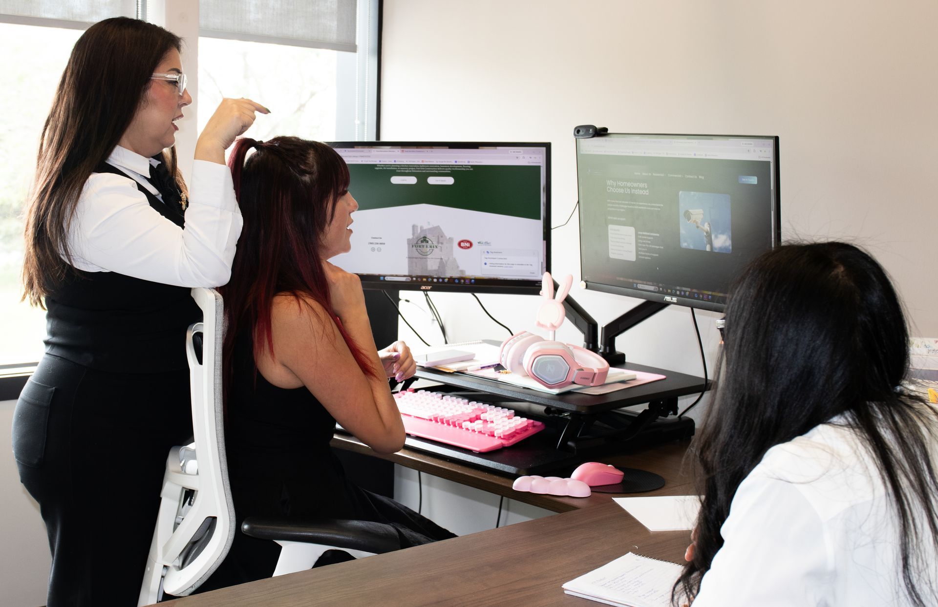 Three woman sat at a office desk discussing a website design