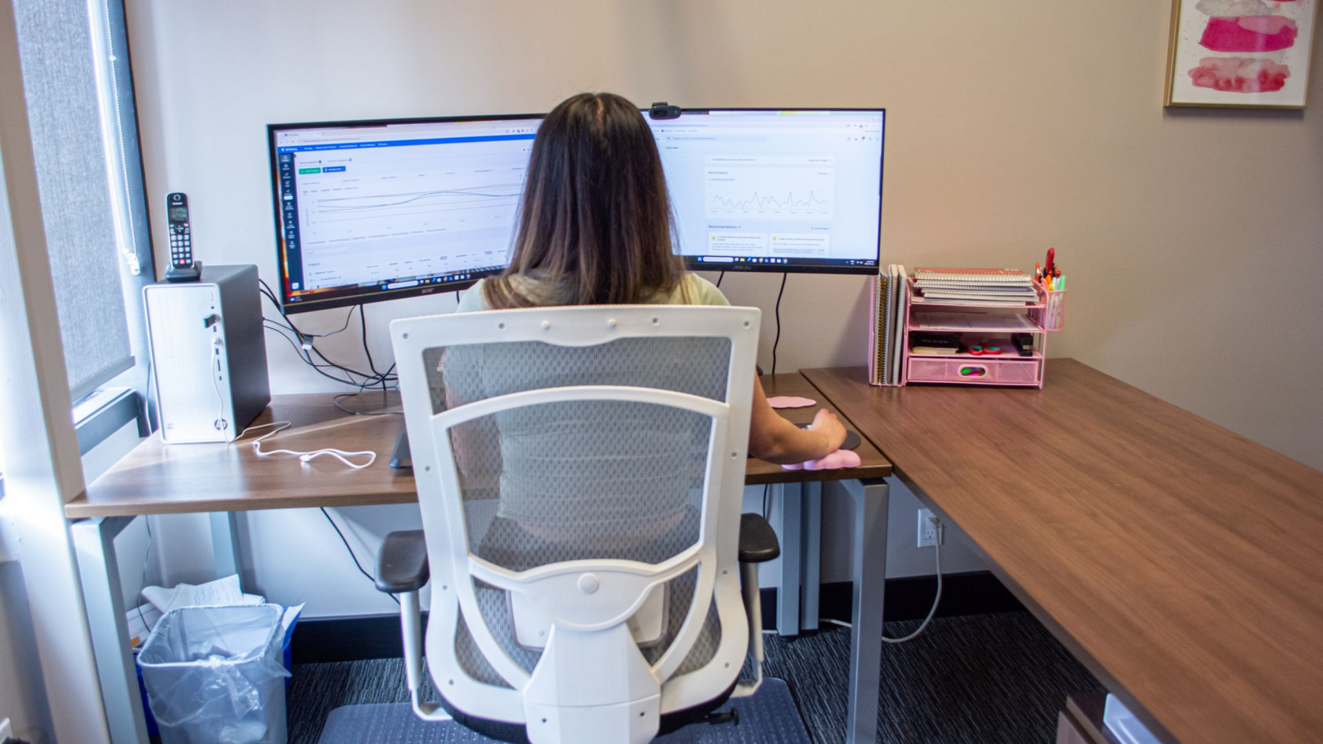 Person seated at a desk facing dual computer monitors in a home office