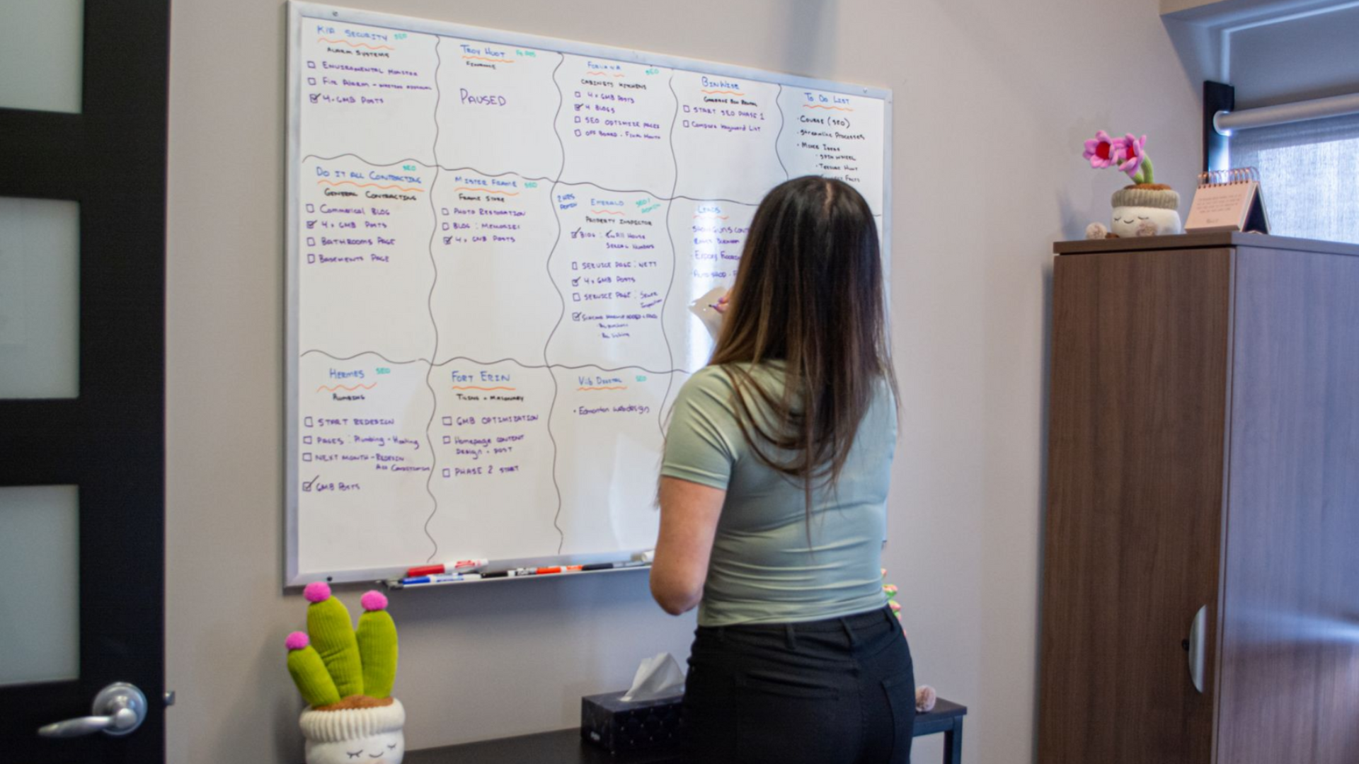 Woman writing on a white board in an office.