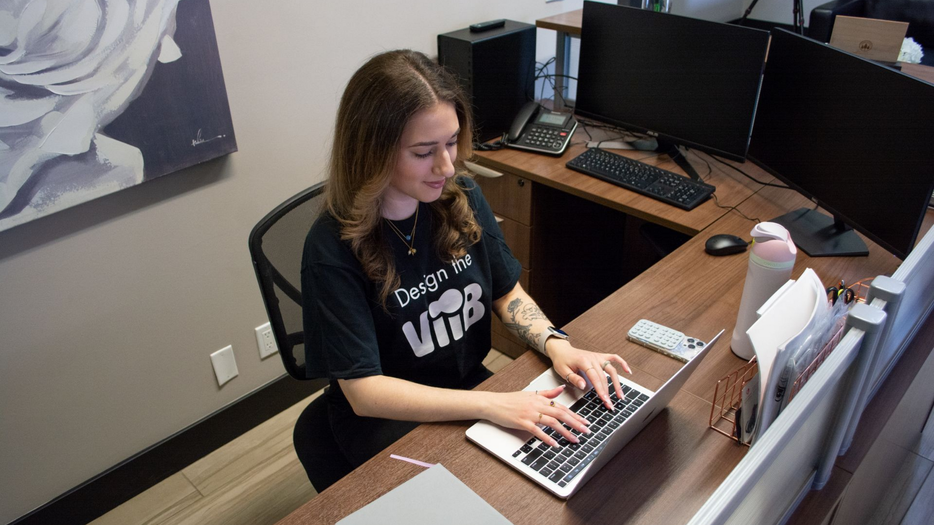 Person seated at a desk facing dual computer monitors in a home office