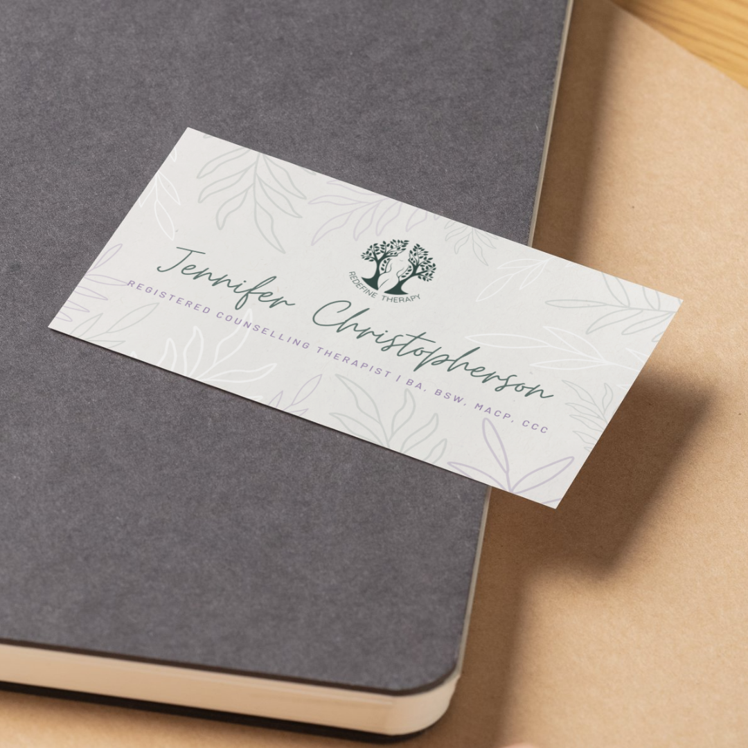 White floral invitation card on a gray notebook and tan envelope; text partially visible.