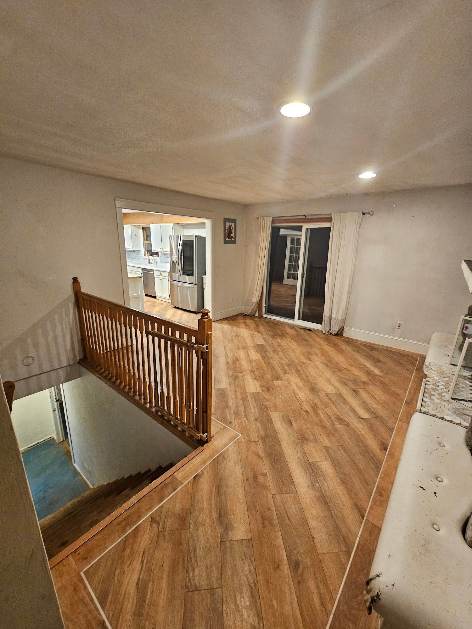 A living room with hardwood floors and a staircase leading to the second floor.