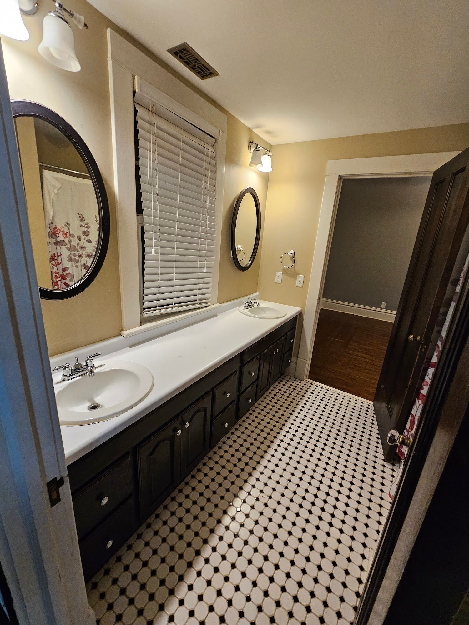 A bathroom with two sinks , a mirror and a window.
