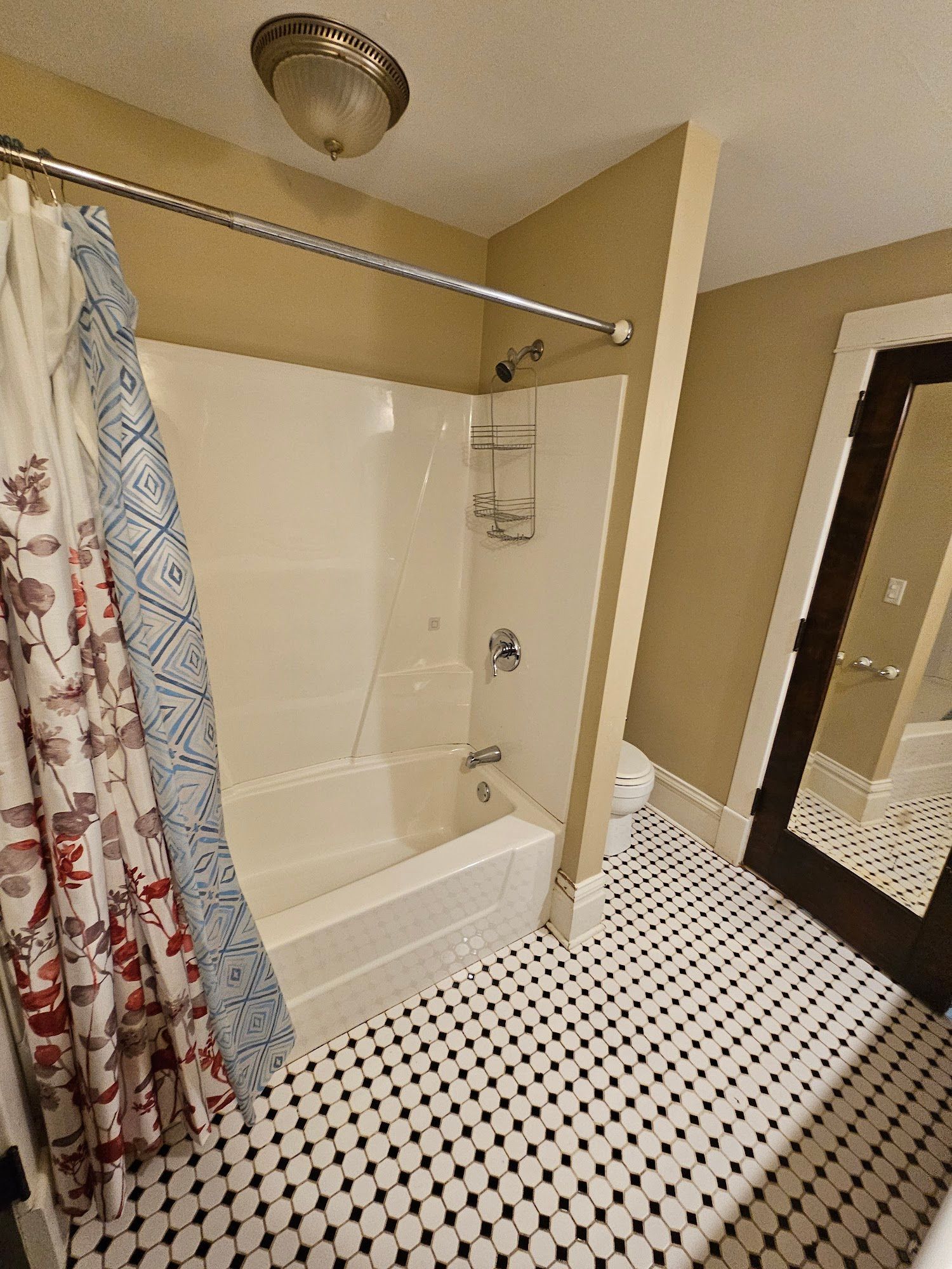 A bathroom with a bathtub , shower , toilet and mirror.