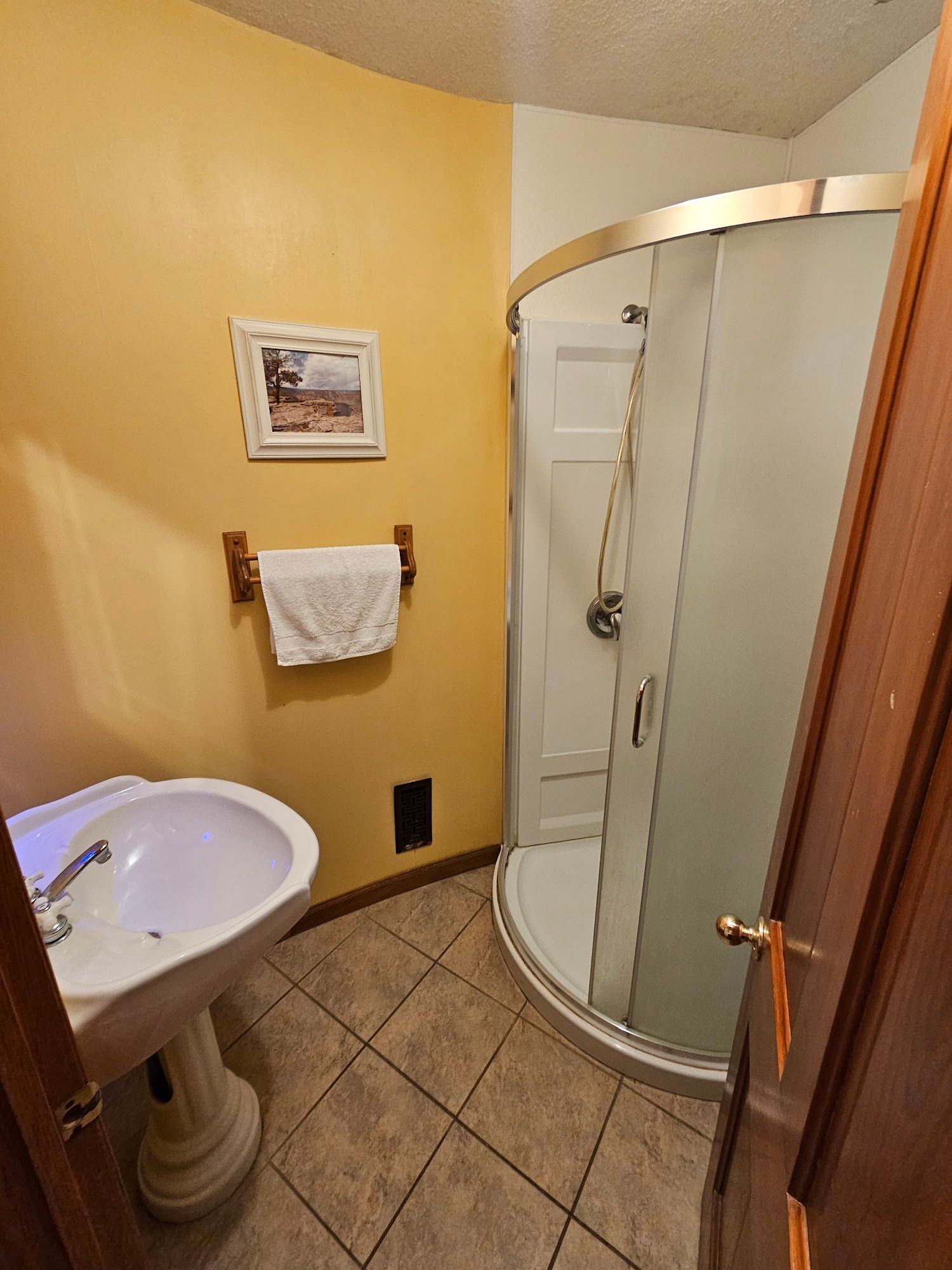 A bathroom with a sink , shower and picture on the wall.