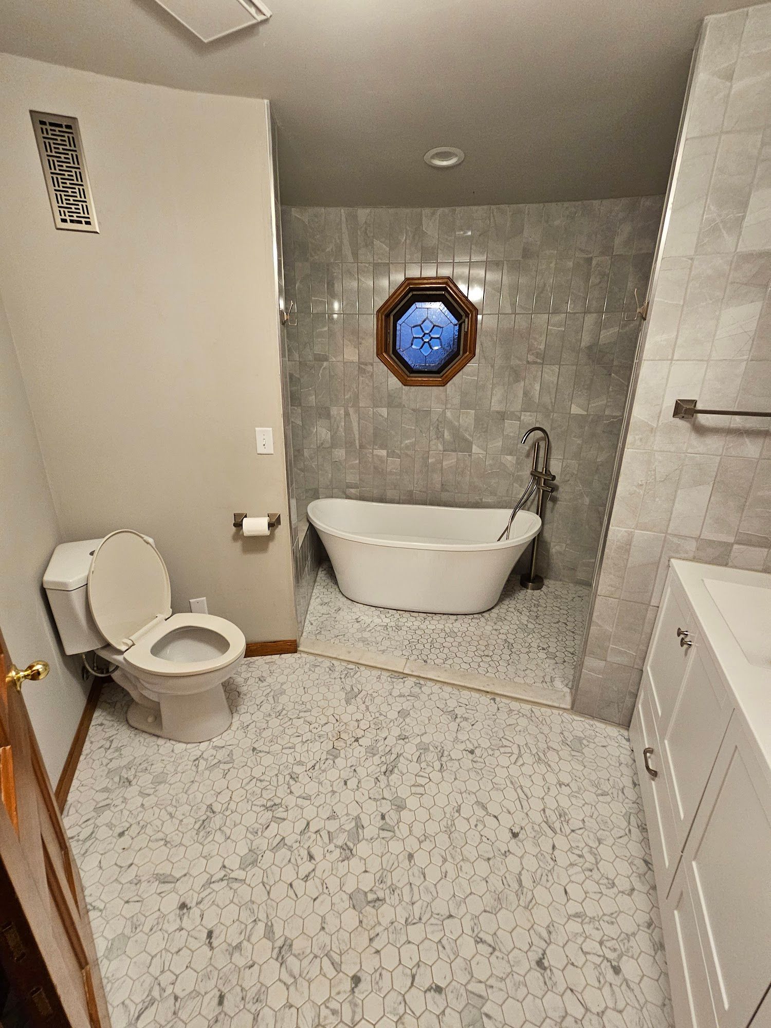 A bathroom with a toilet , sink , tub and window.