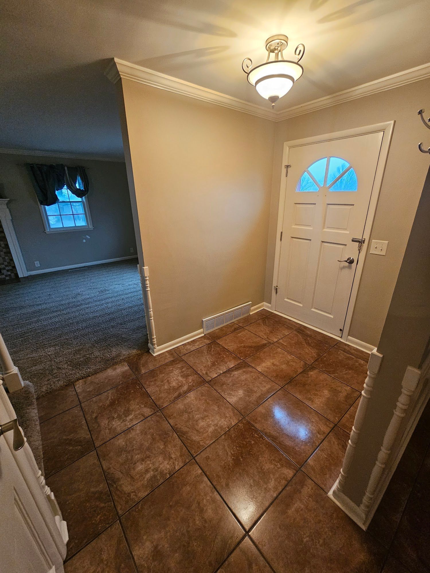 A hallway with a tiled floor and a white door in a house.