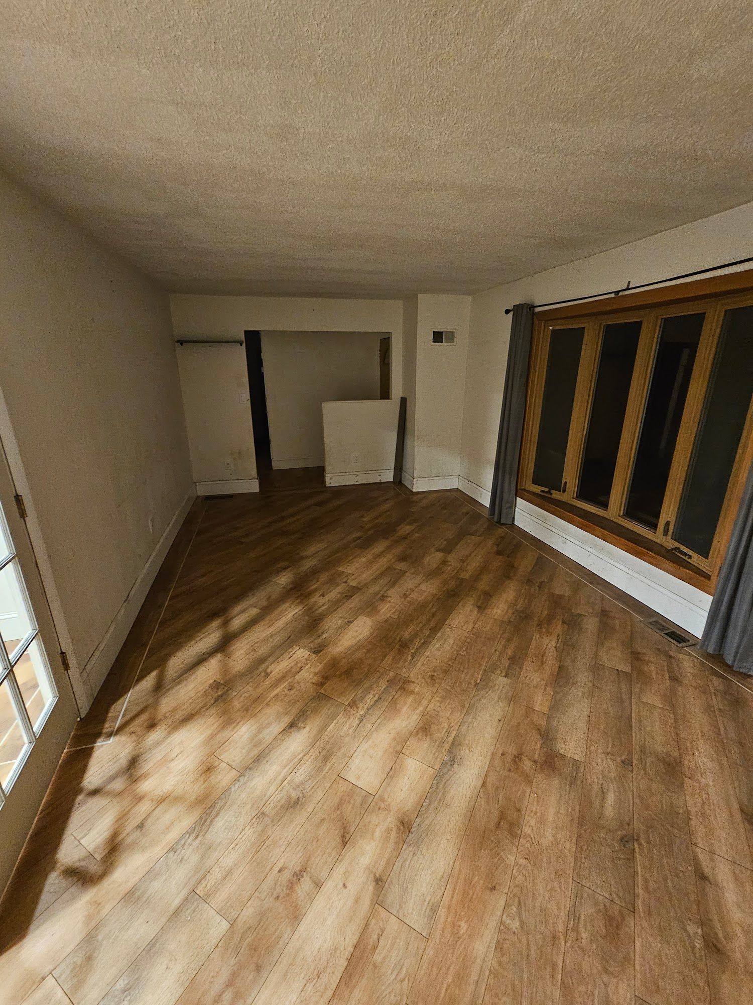 An empty living room with hardwood floors and a window.
