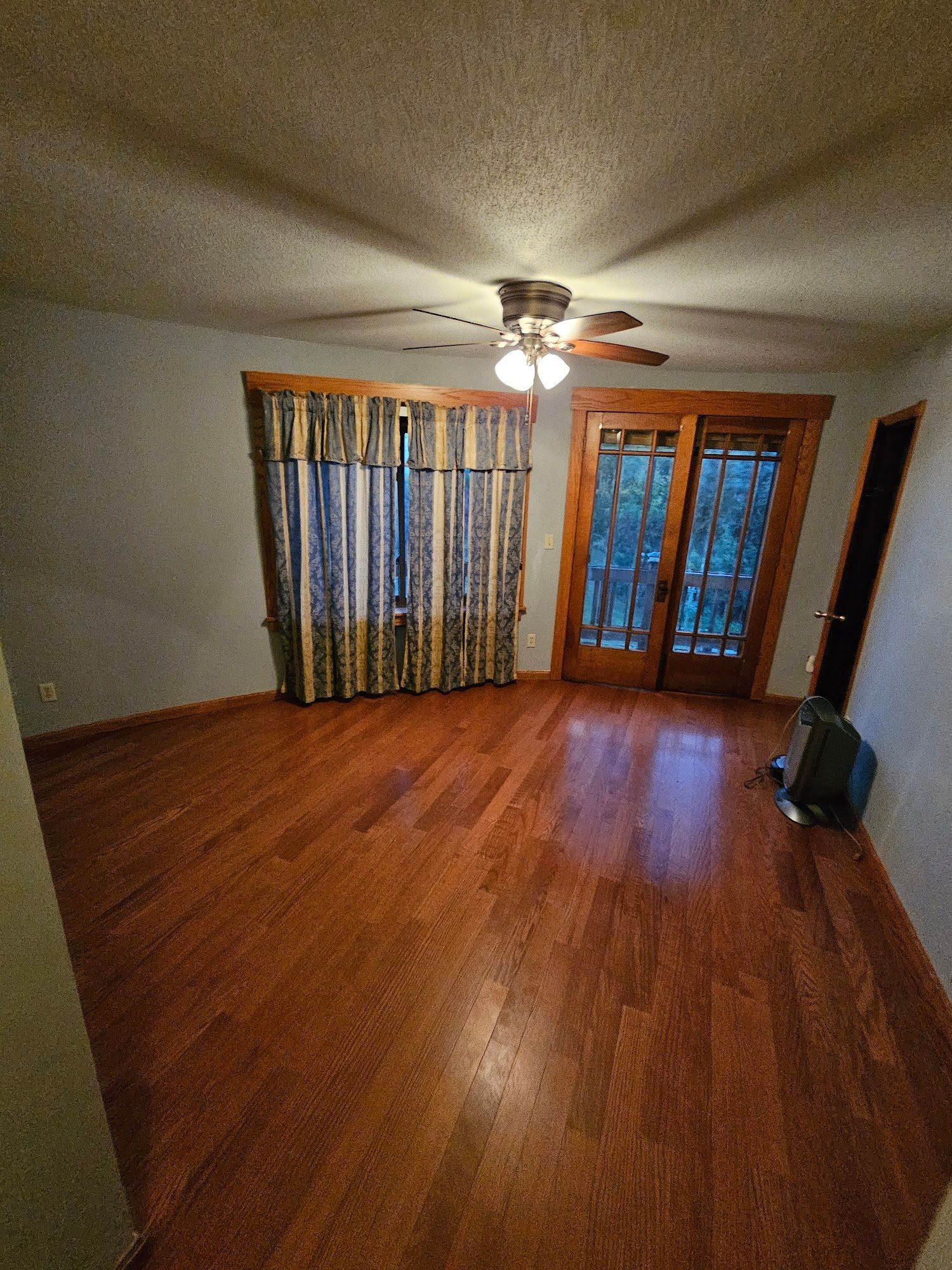 A living room with hardwood floors and a ceiling fan.