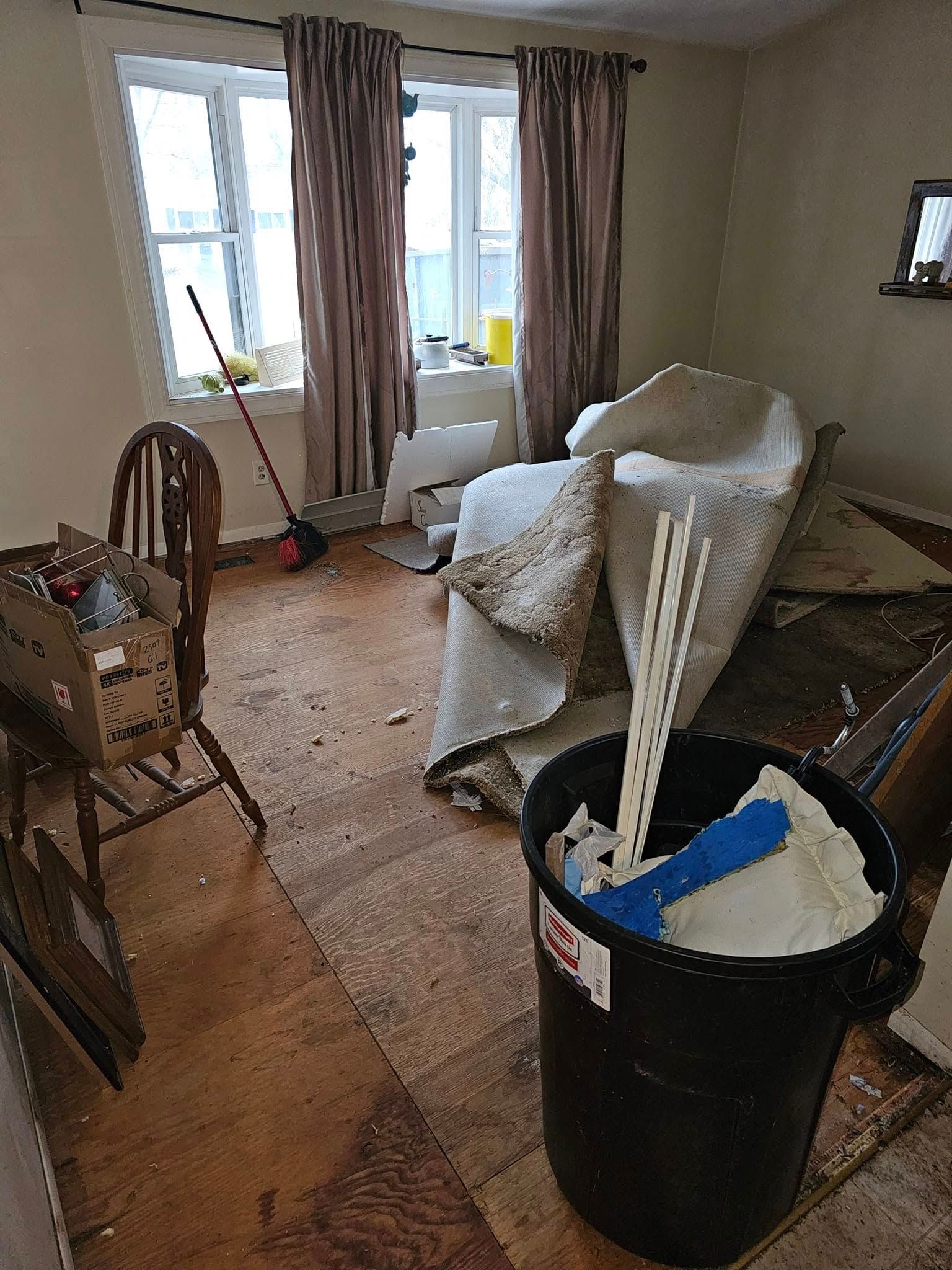 There is a trash can in the middle of the room with a mop in it.