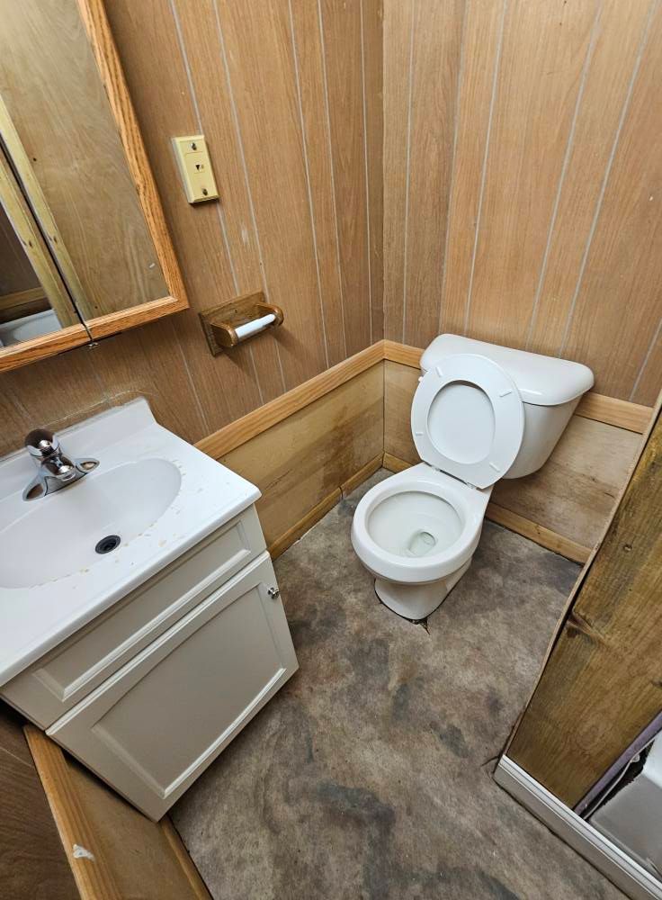 A bathroom with a toilet , sink and mirror.