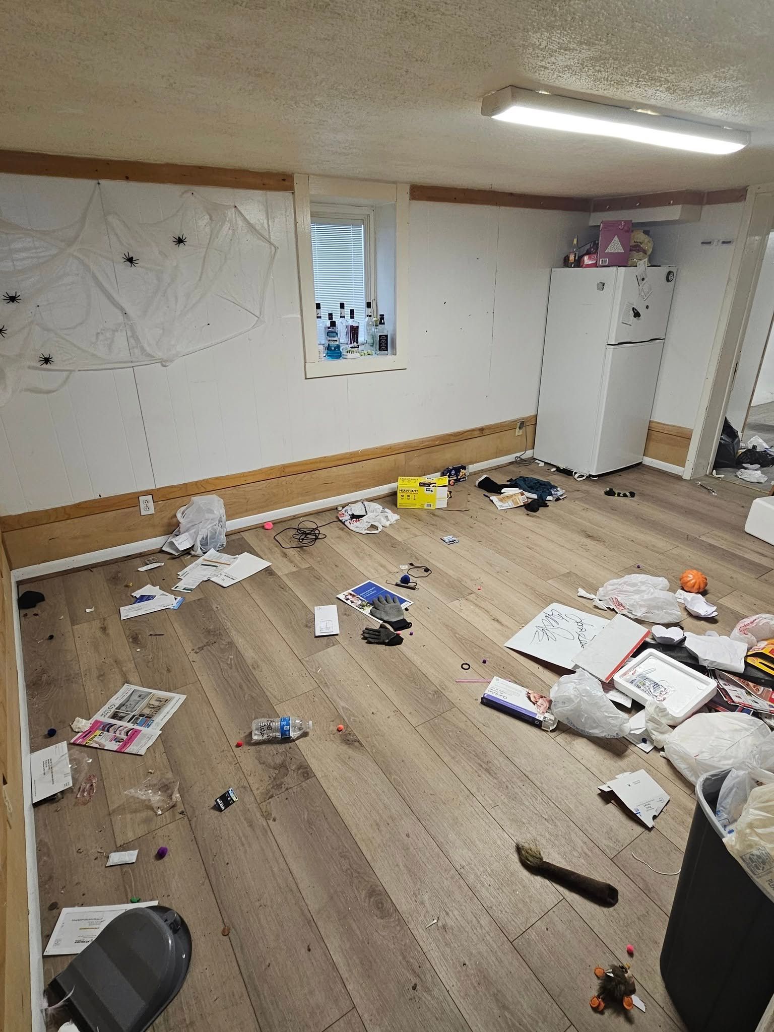 A room with a lot of trash on the floor and a window.