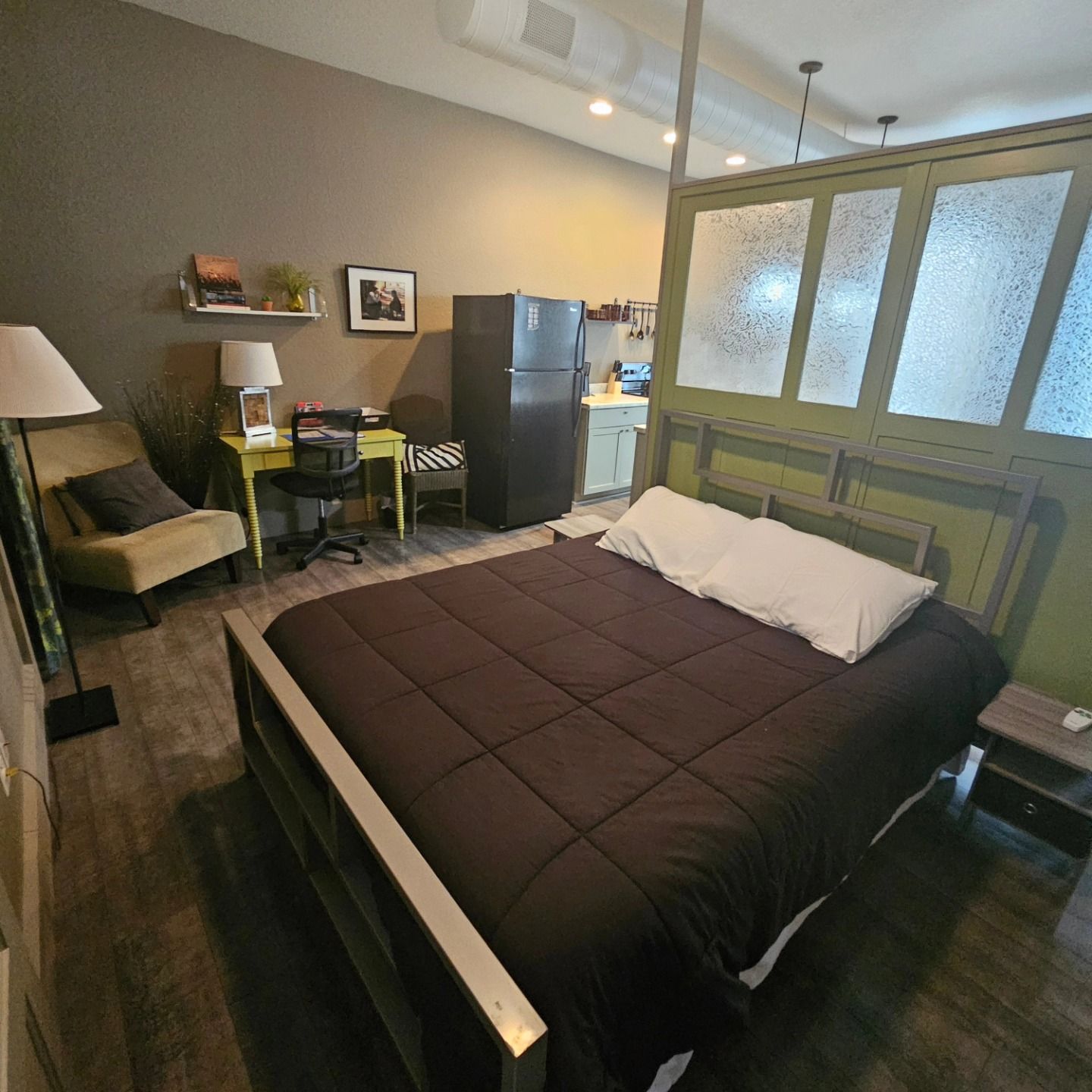 A bedroom with a large bed and a refrigerator