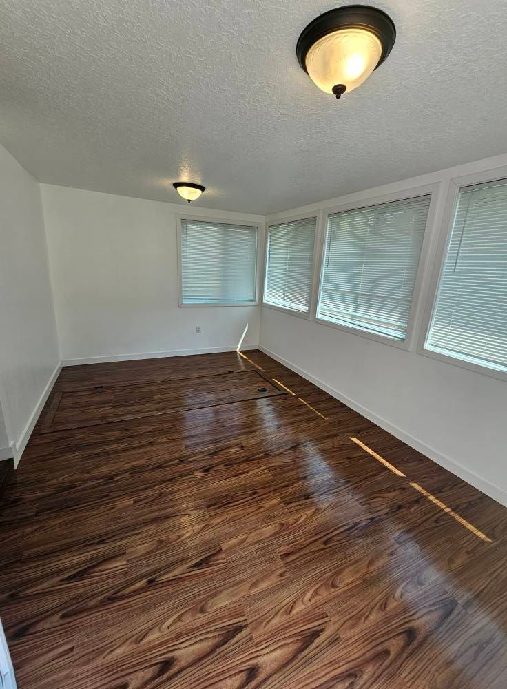 An empty living room with hardwood floors and white walls.