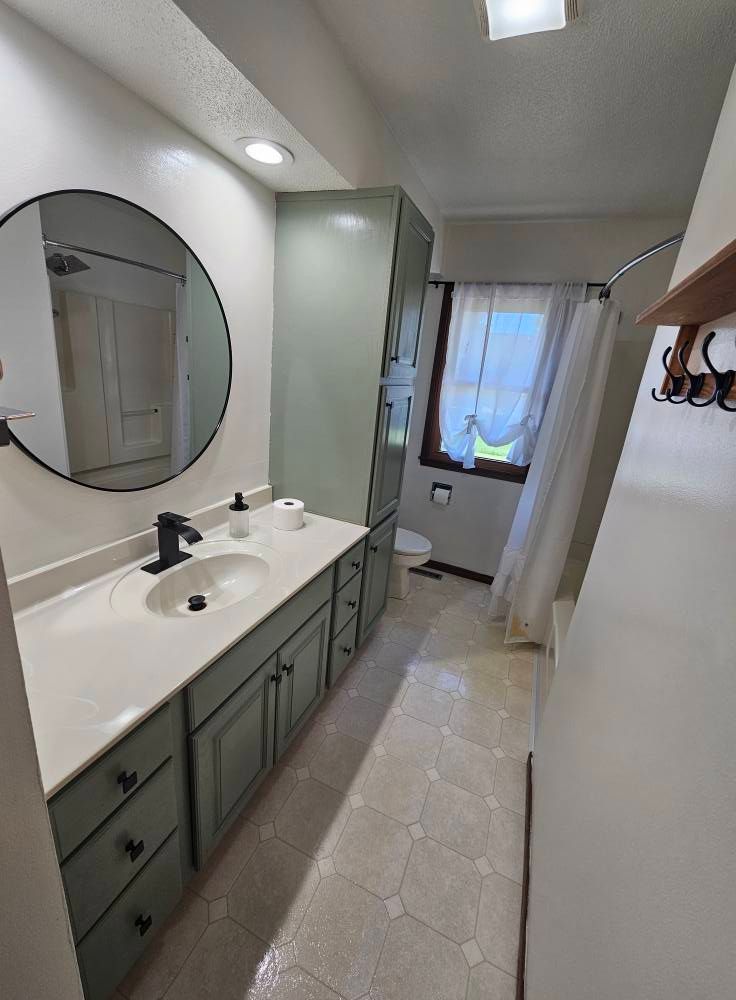 A bathroom with a sink , mirror and toilet.