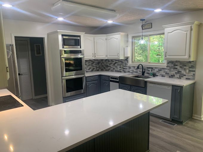 A kitchen with white cabinets , stainless steel appliances , a sink , and a large island.