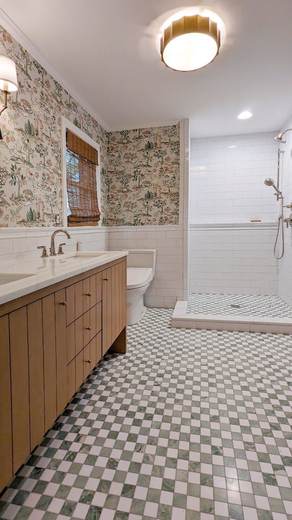 A bathroom with two sinks , a toilet , and a walk in shower.