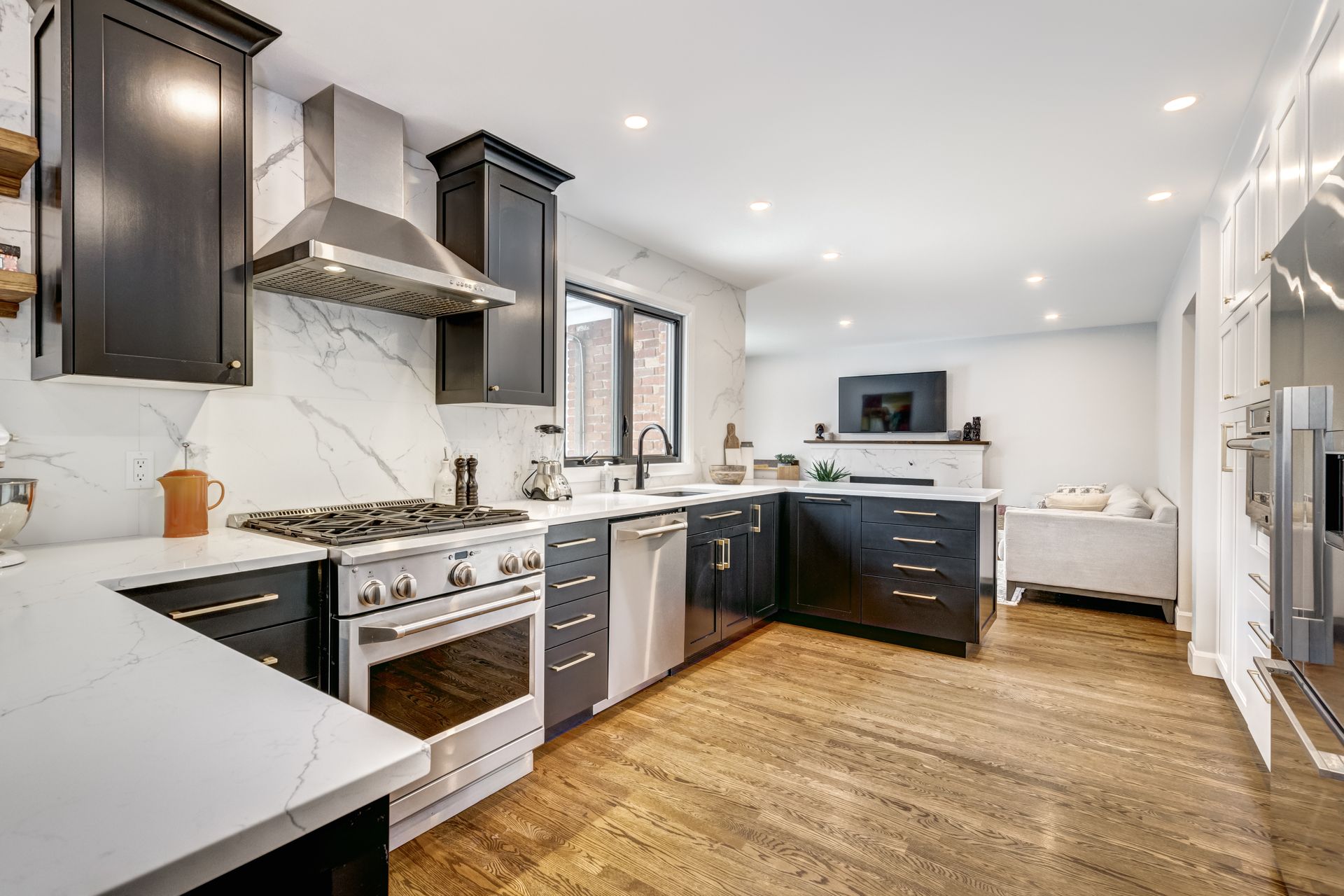 A kitchen with white cabinets , stainless steel appliances , a sink , and a large island.