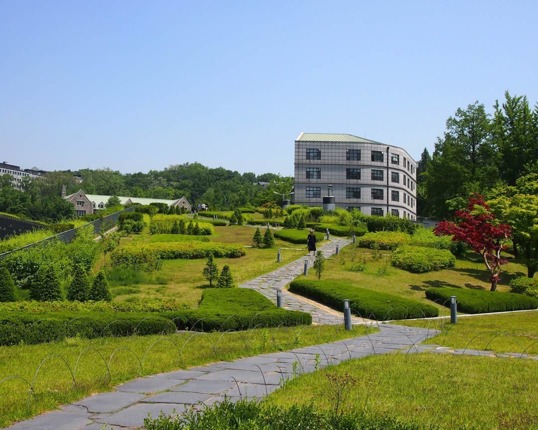 A large building is surrounded by a lush green park.