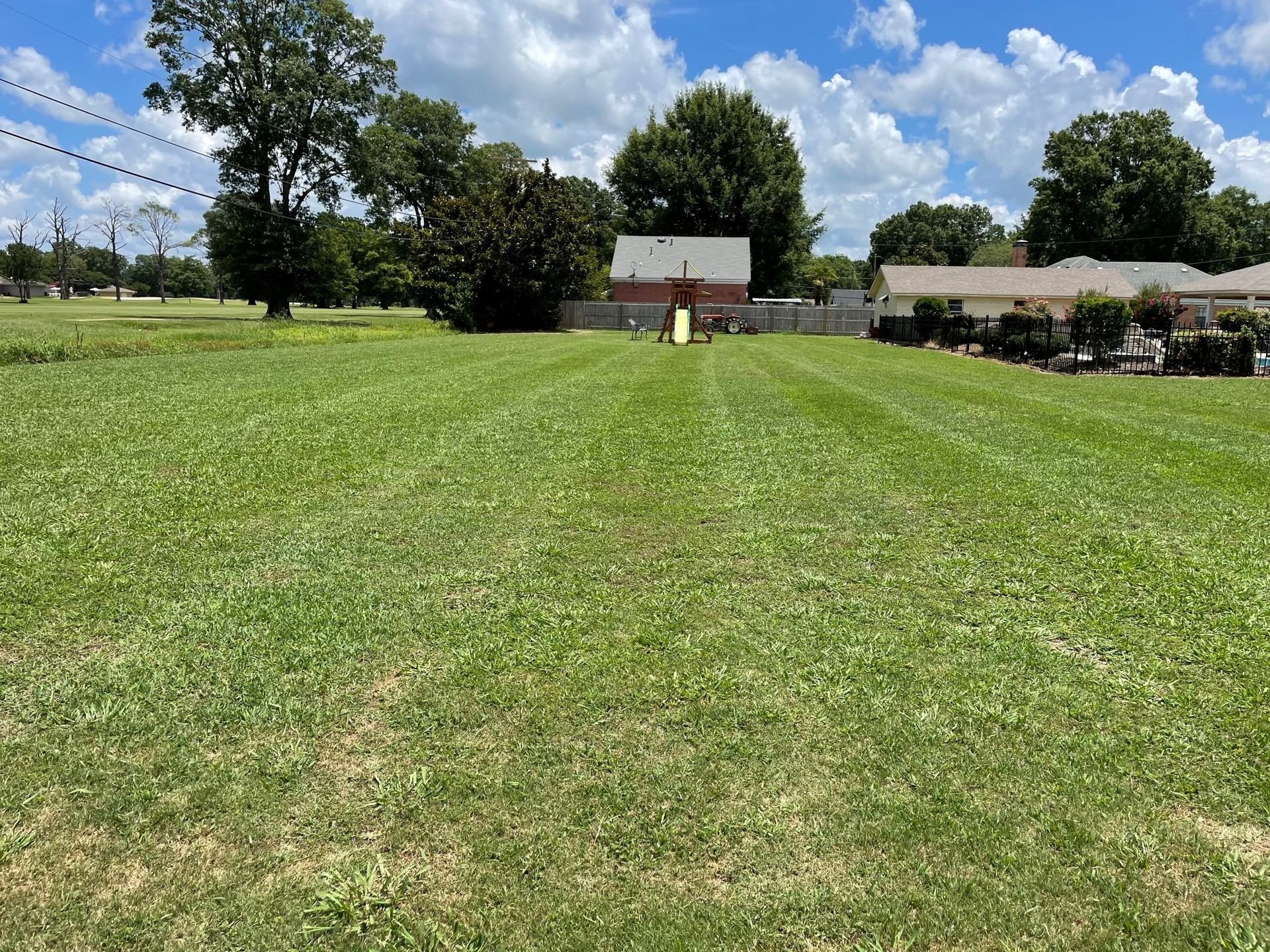 A large lush green field with a house in the background.