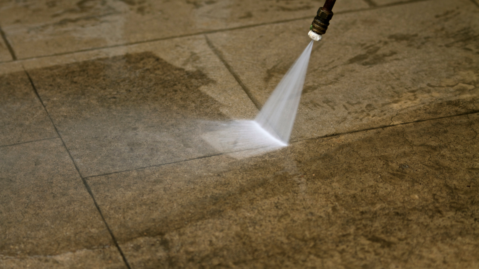 A person is using a high pressure washer to clean a tiled floor.