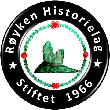 Rundt emblem: «Røyken Historielag» med 1966, svart kant, grønt og rødt blomstermønster og en grønn landskapsskildring.