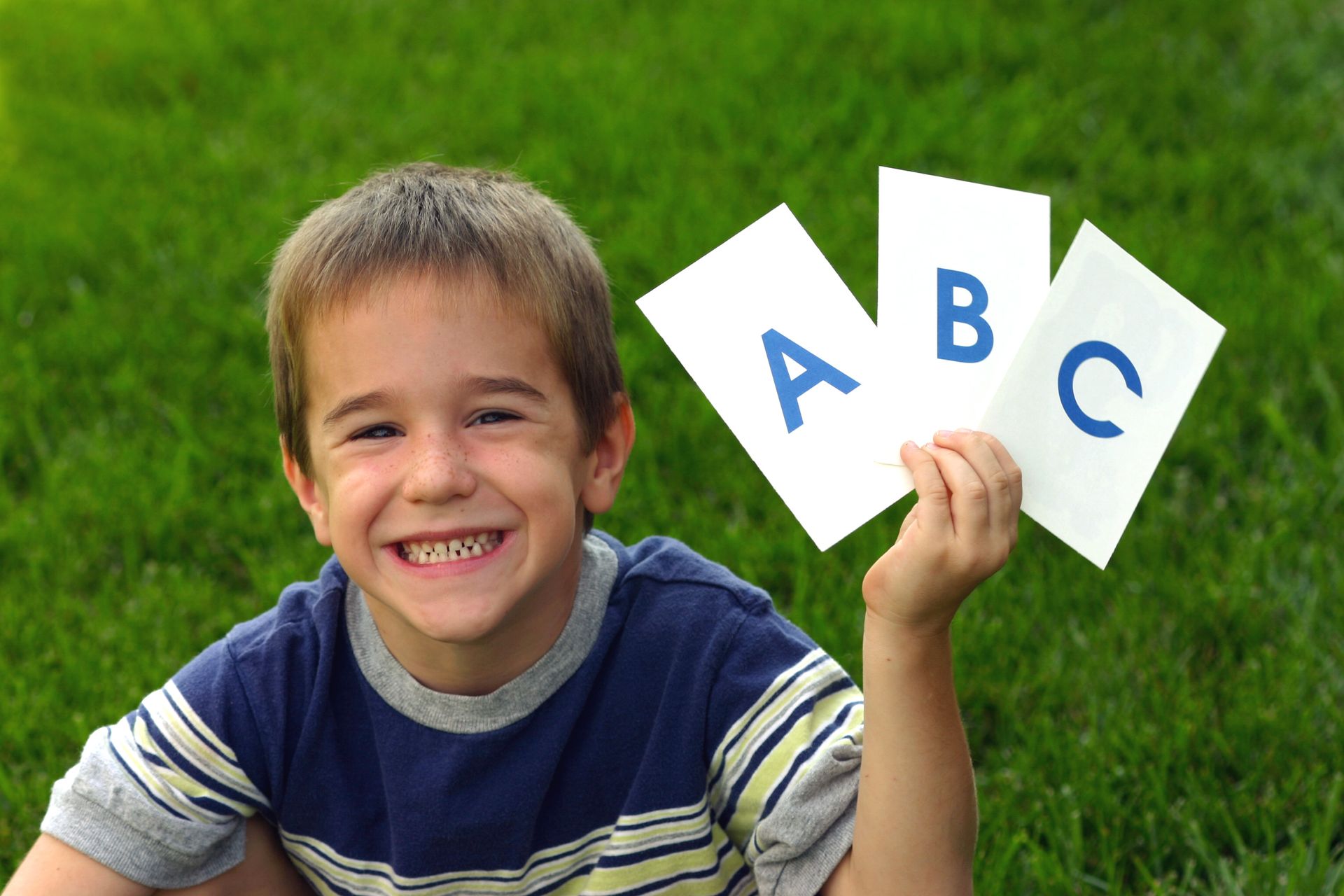 A child is holding up three cards that spell out A B C