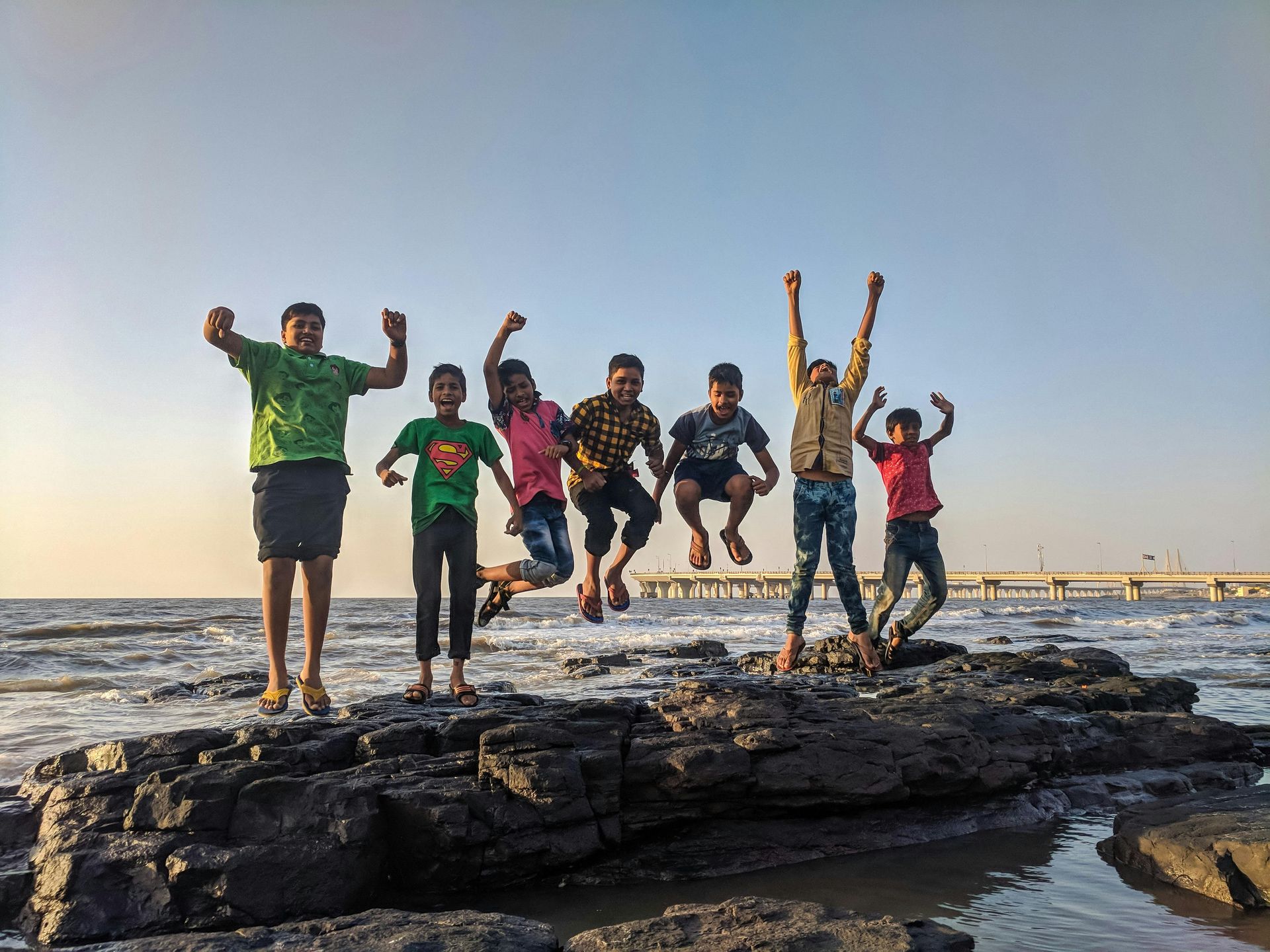 A group of children at jumping on rocks at the beach