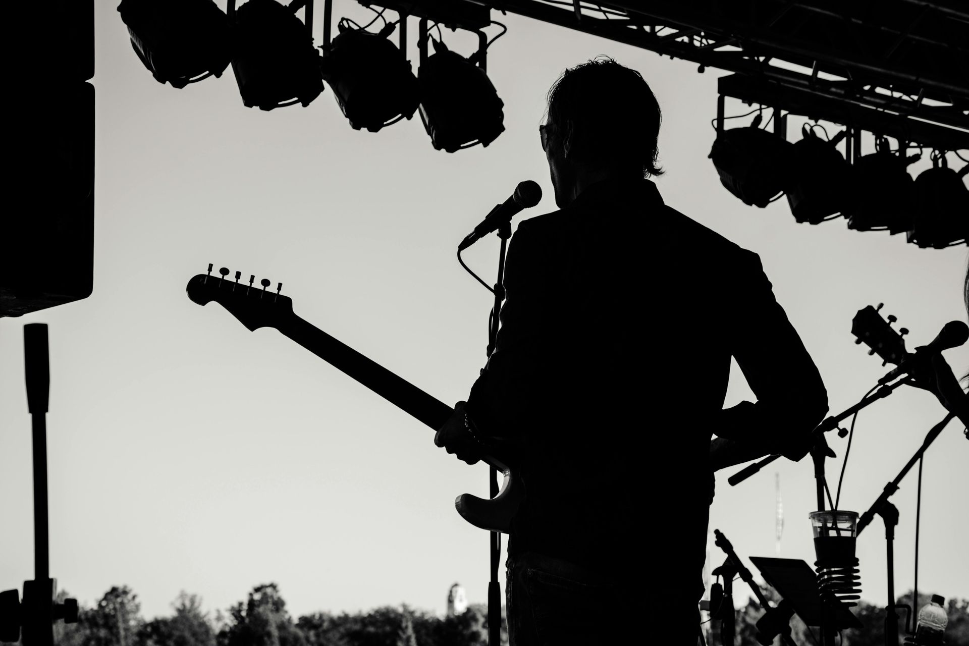 Silhouette of guitarist playing on stage under spotlights.