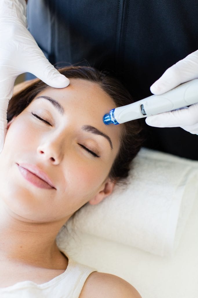 A woman is getting a hydrafacial treatment on her forehead at Results Skincare Studio in Fort Myers