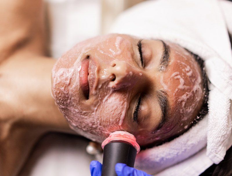 A woman is getting a Oxygeneo facial treatment at Results Skincare Studio in Fort Myers