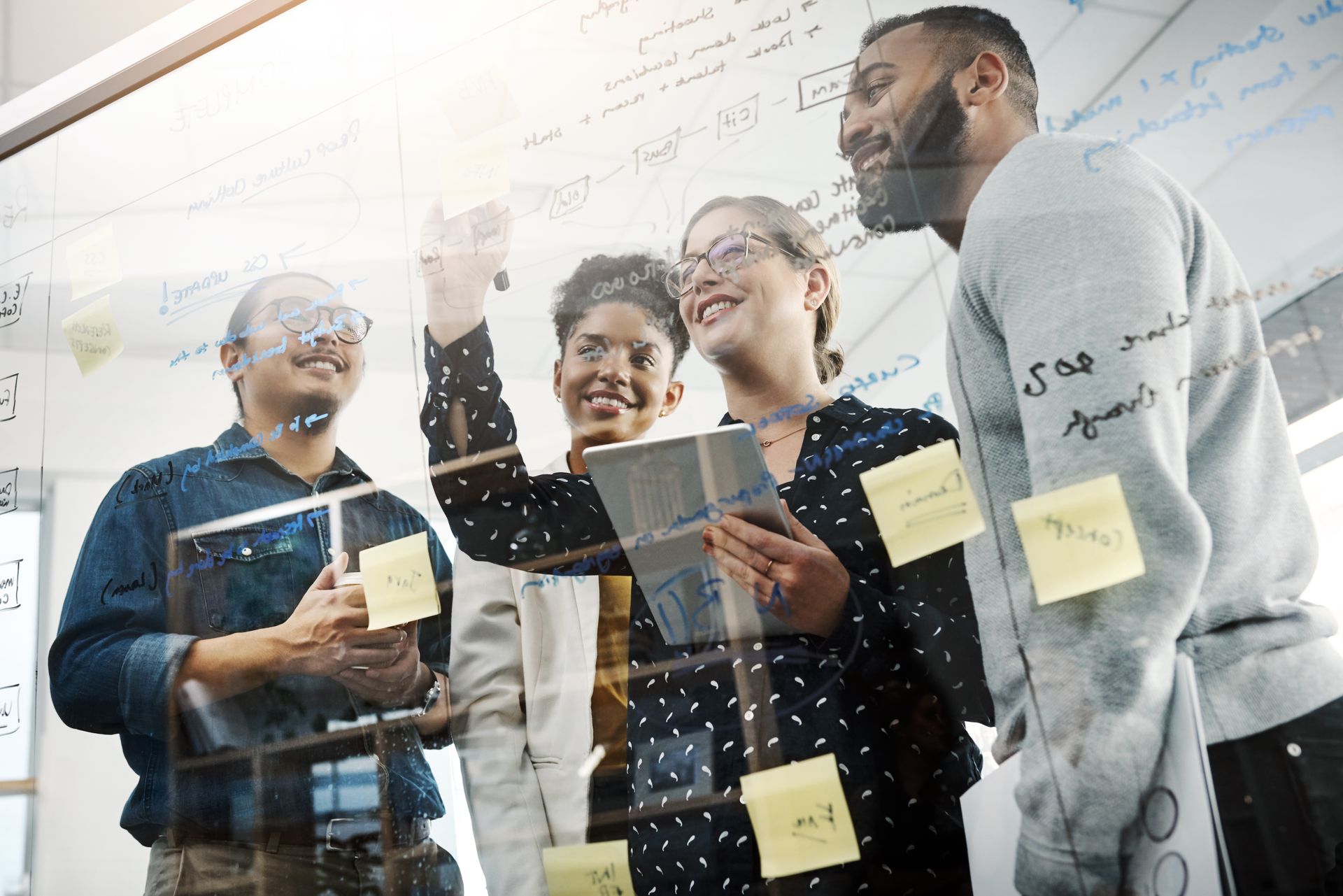 a group of people looking at a white board with sticky notes on it