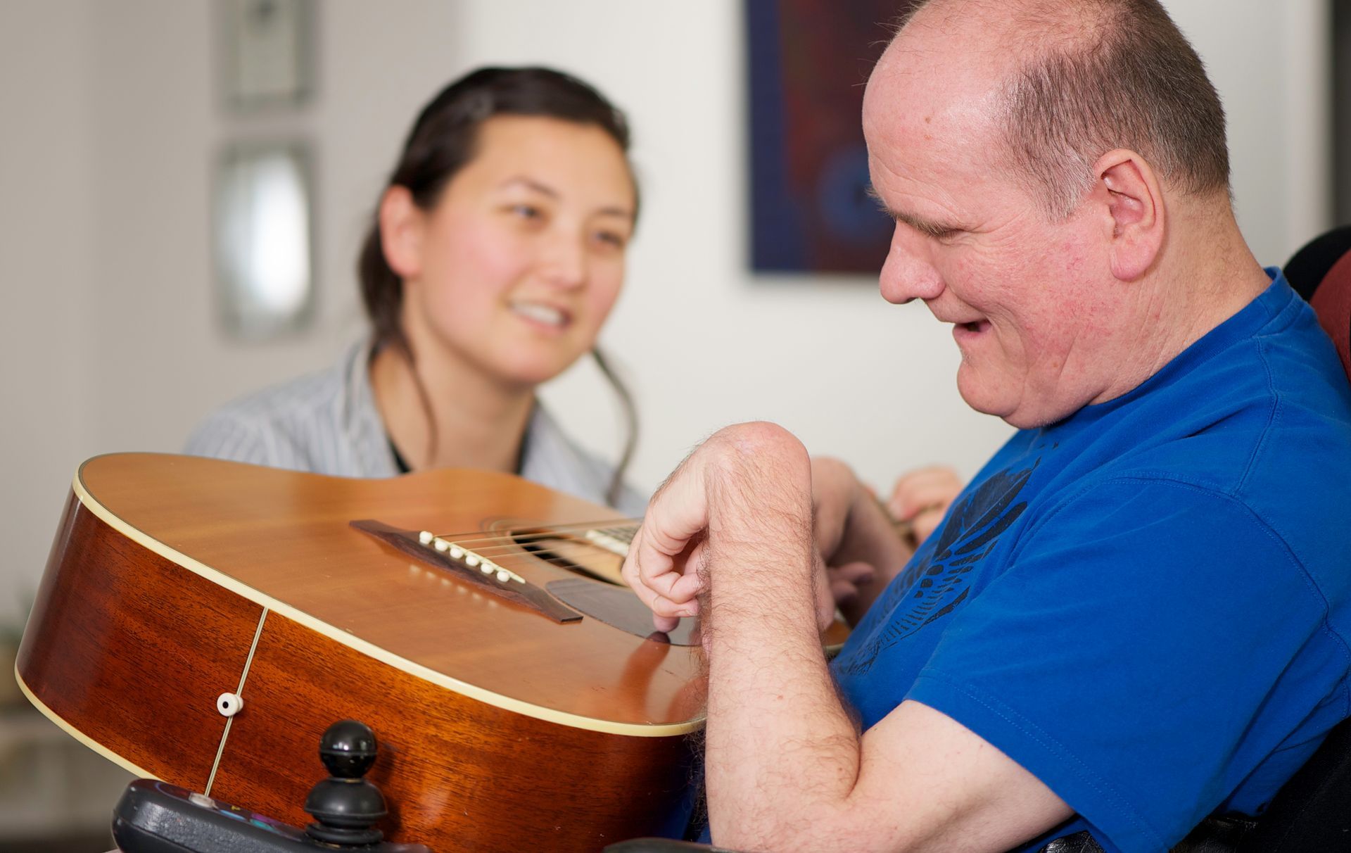a man in a blue shirt is playing an acoustic guitar
