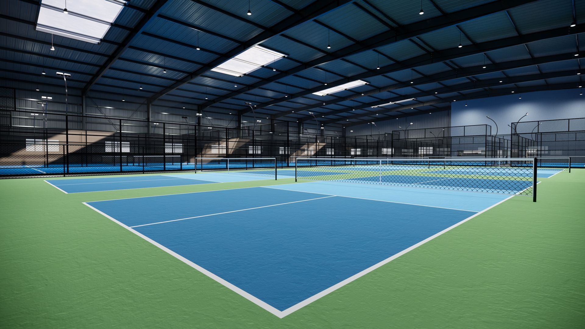 Indoor tennis court with blue playing surface, green surrounding area, and overhead lights