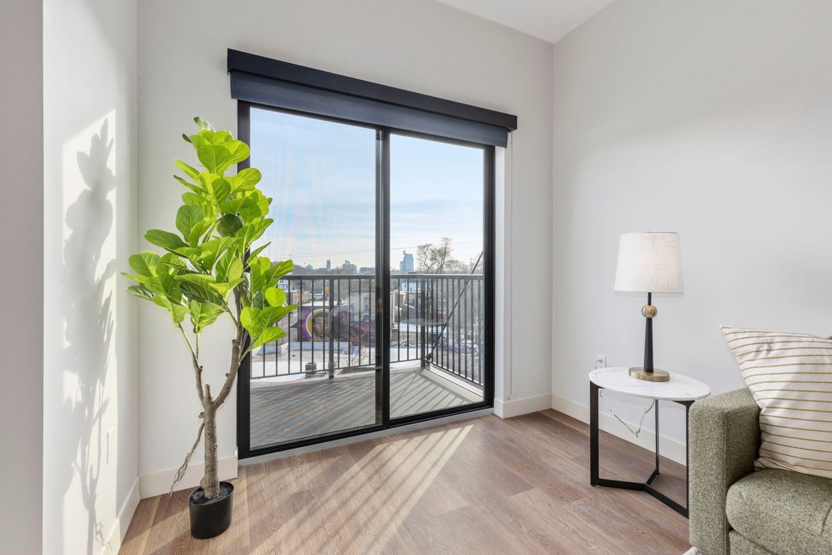 Bright living room with a potted plant, sliding glass doors, and a small side table beside a sofa.
