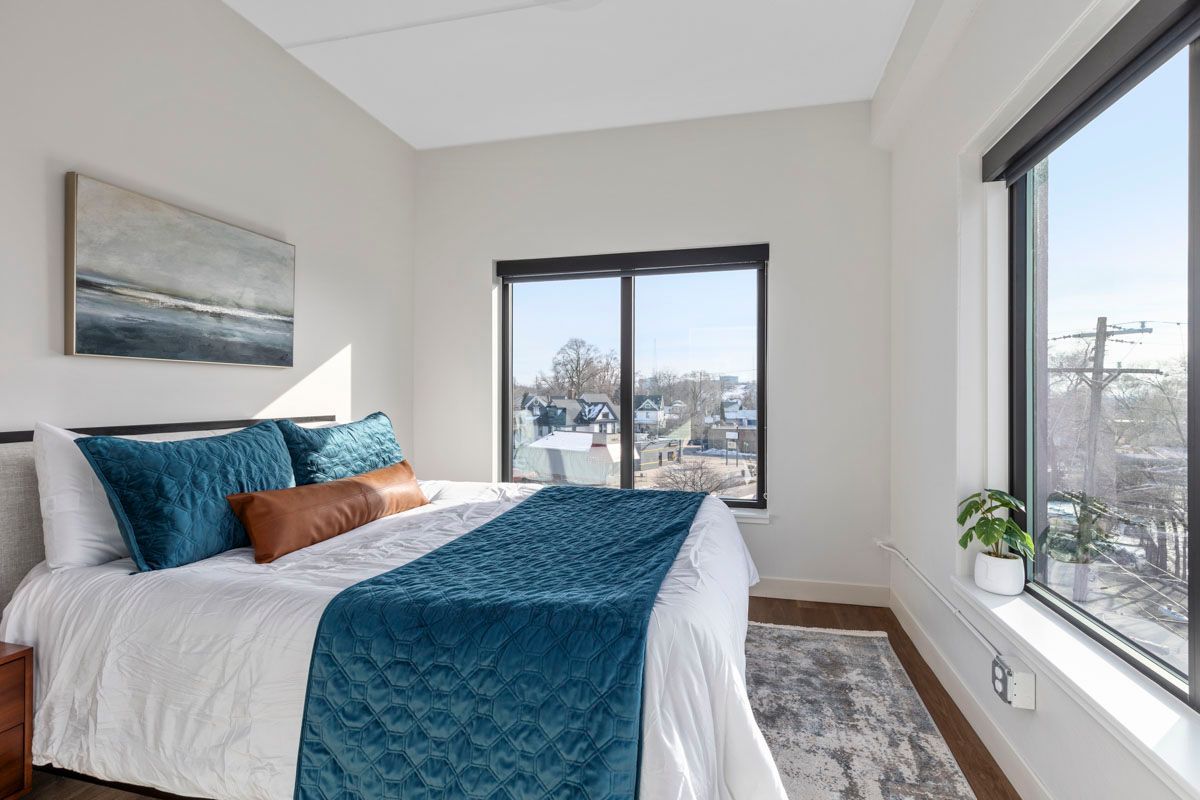 Bright bedroom with teal bedding, large windows, and a snowy view outside