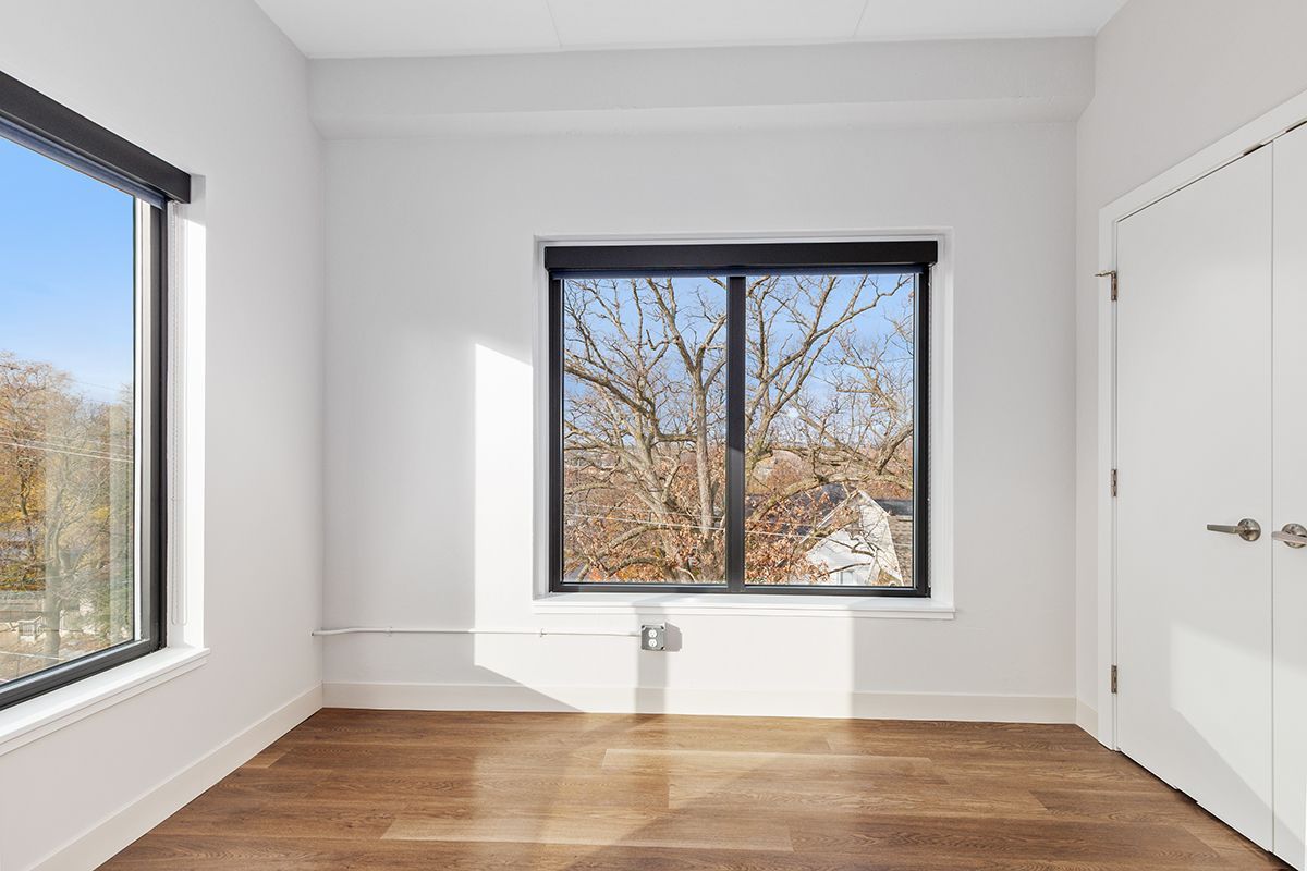 Empty bright room with white walls, hardwood floor, and two windows