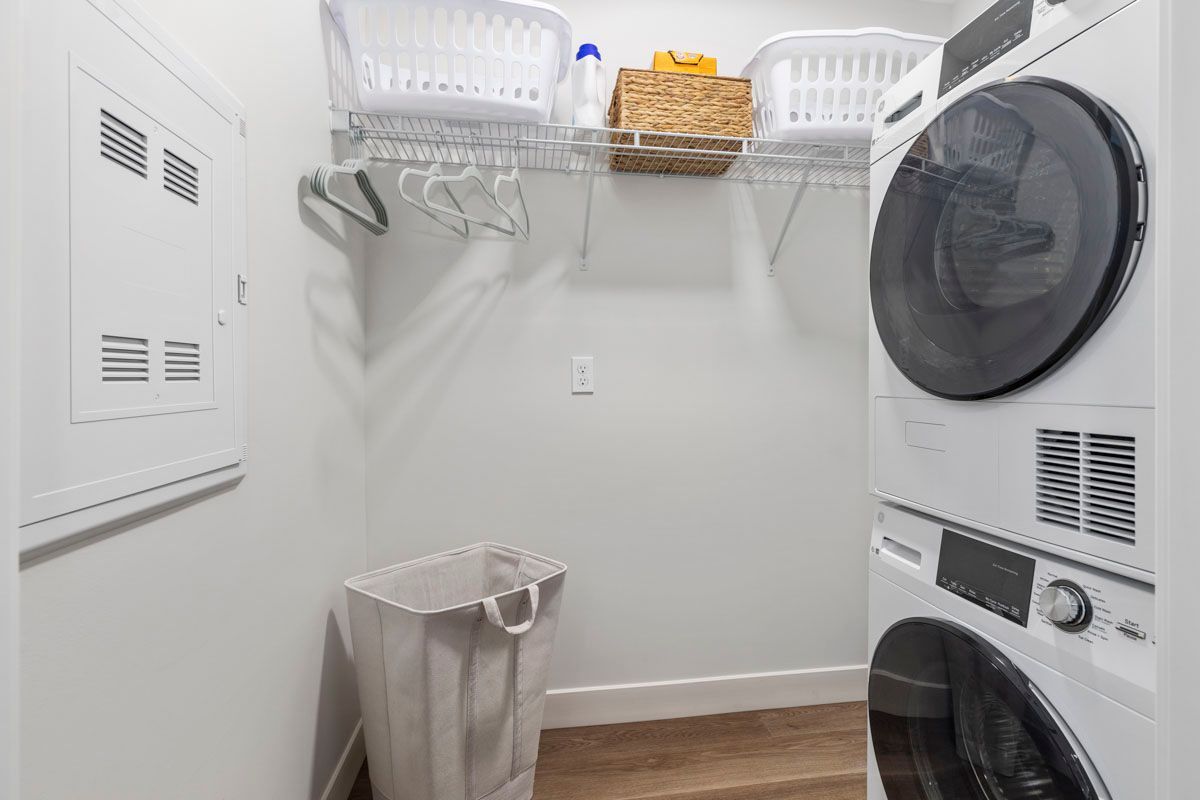Laundry room with washer and dryer, wire shelves, a trash bin, and a basket on the top shelf.