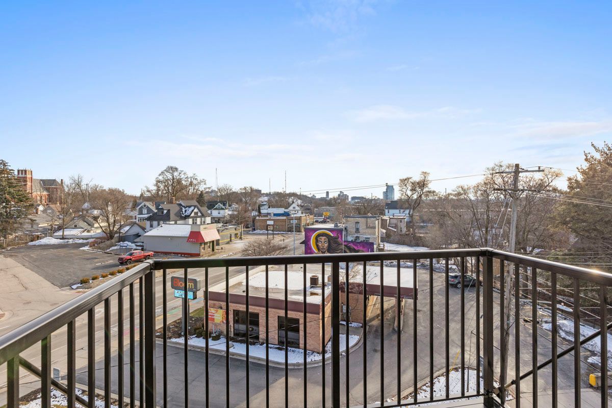 Balcony view over a snowy neighborhood with rooftops, trees, and a clear blue sky