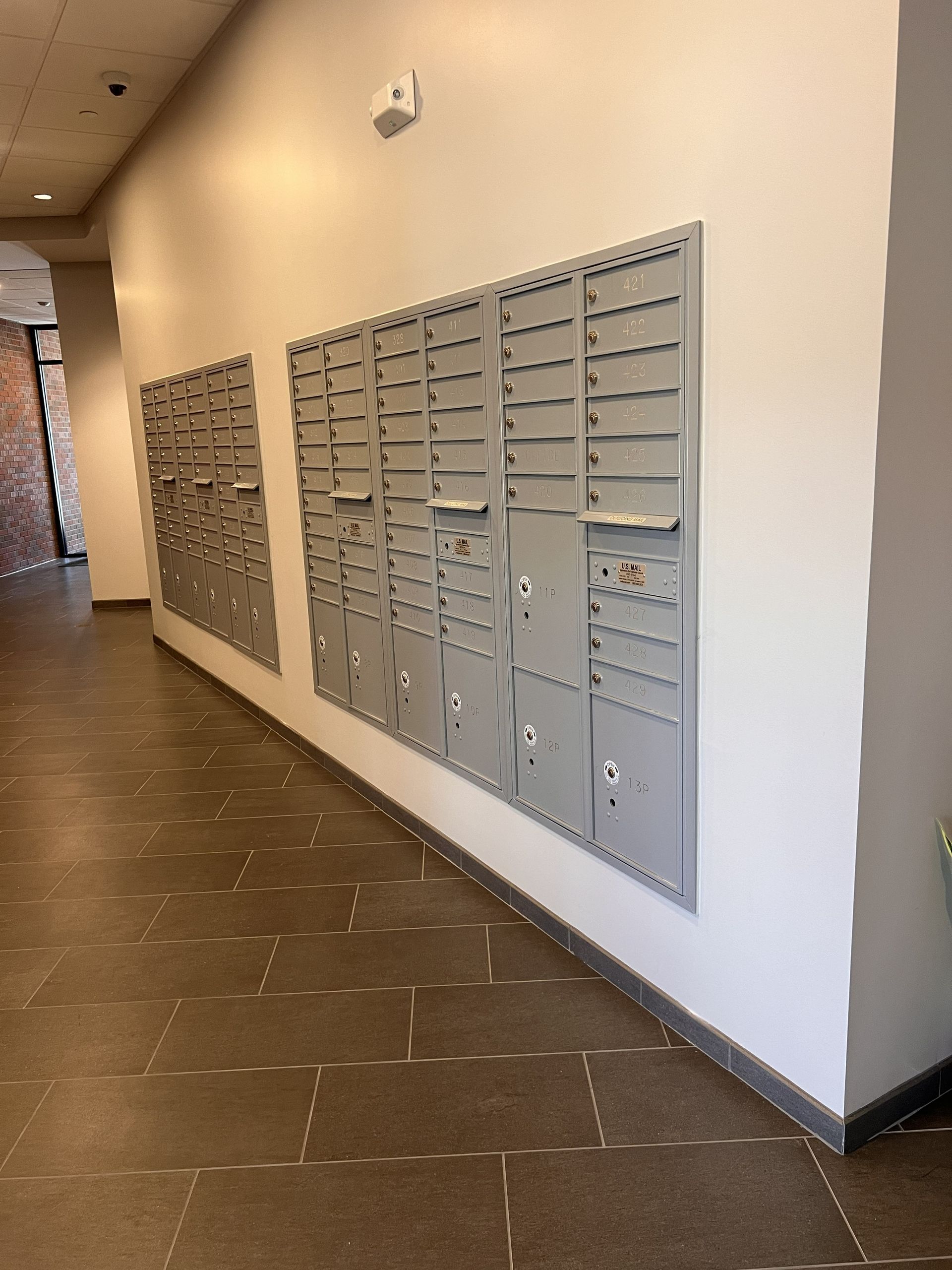 Hallway with rows of wall-mounted mailboxes on a white wall and tiled floor