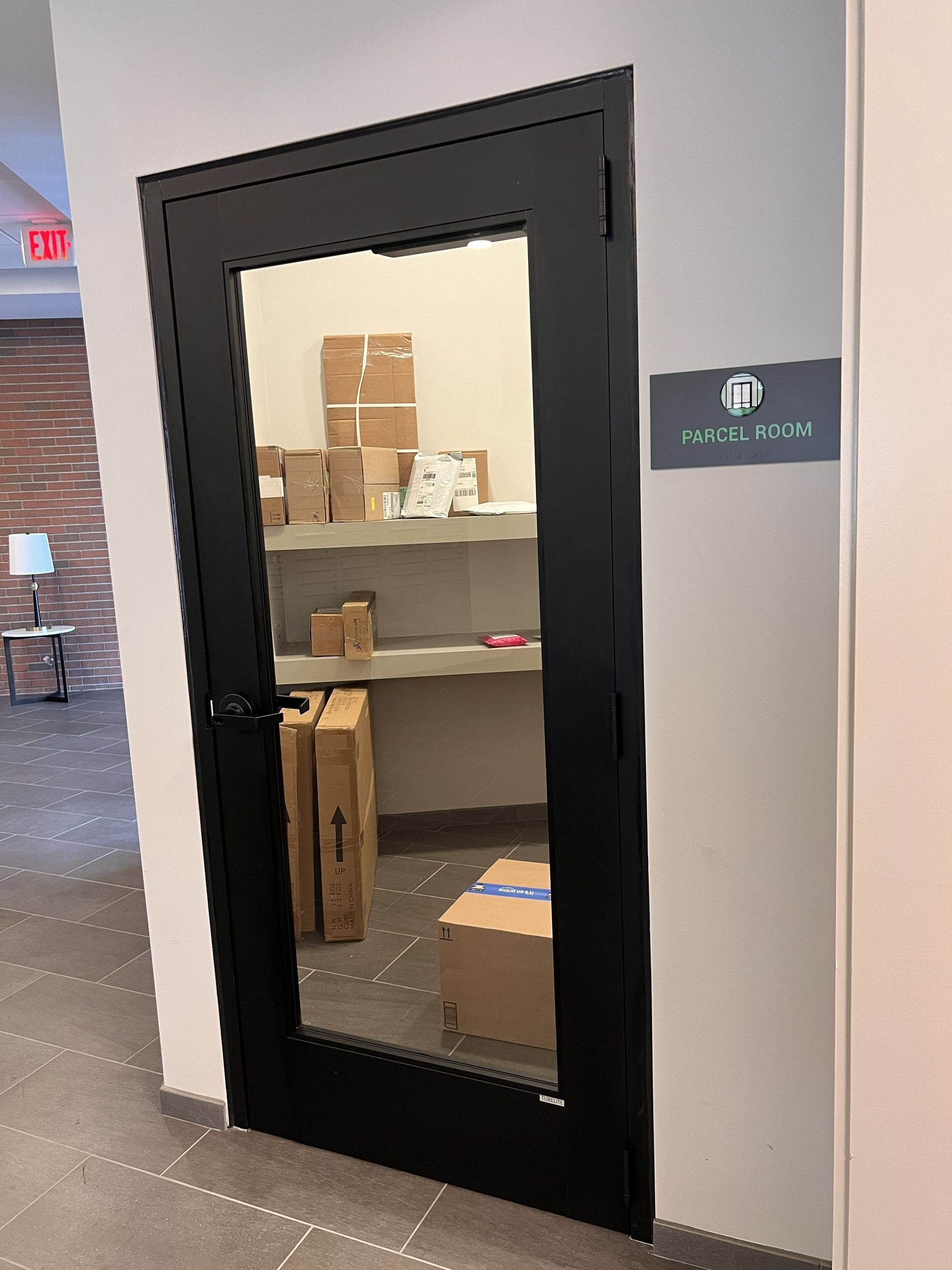 Glass-front storage closet with stacked boxes and supplies in an office hallway