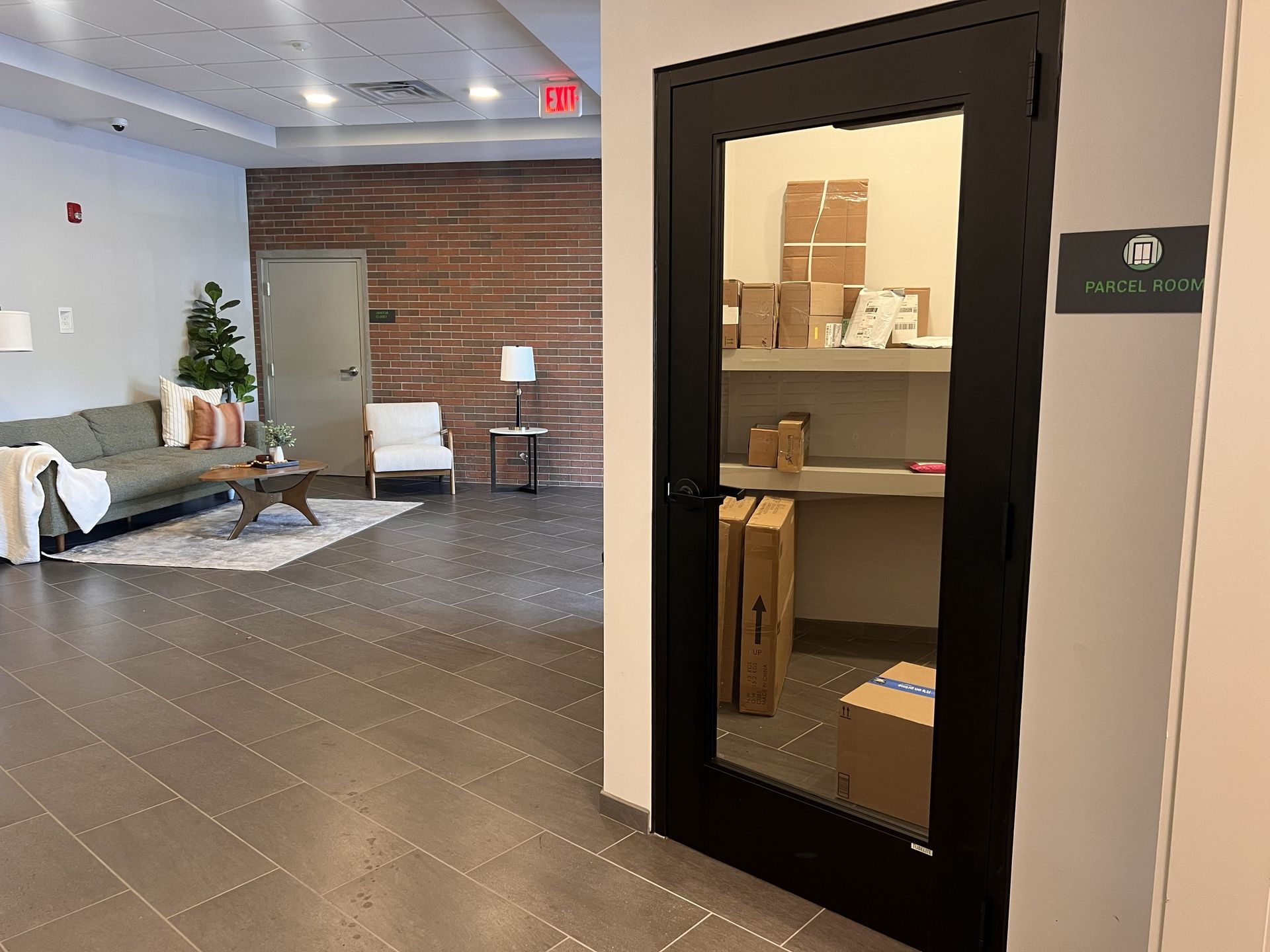 Office lobby hallway with seating, tiled floor, and a glass display door on the right.