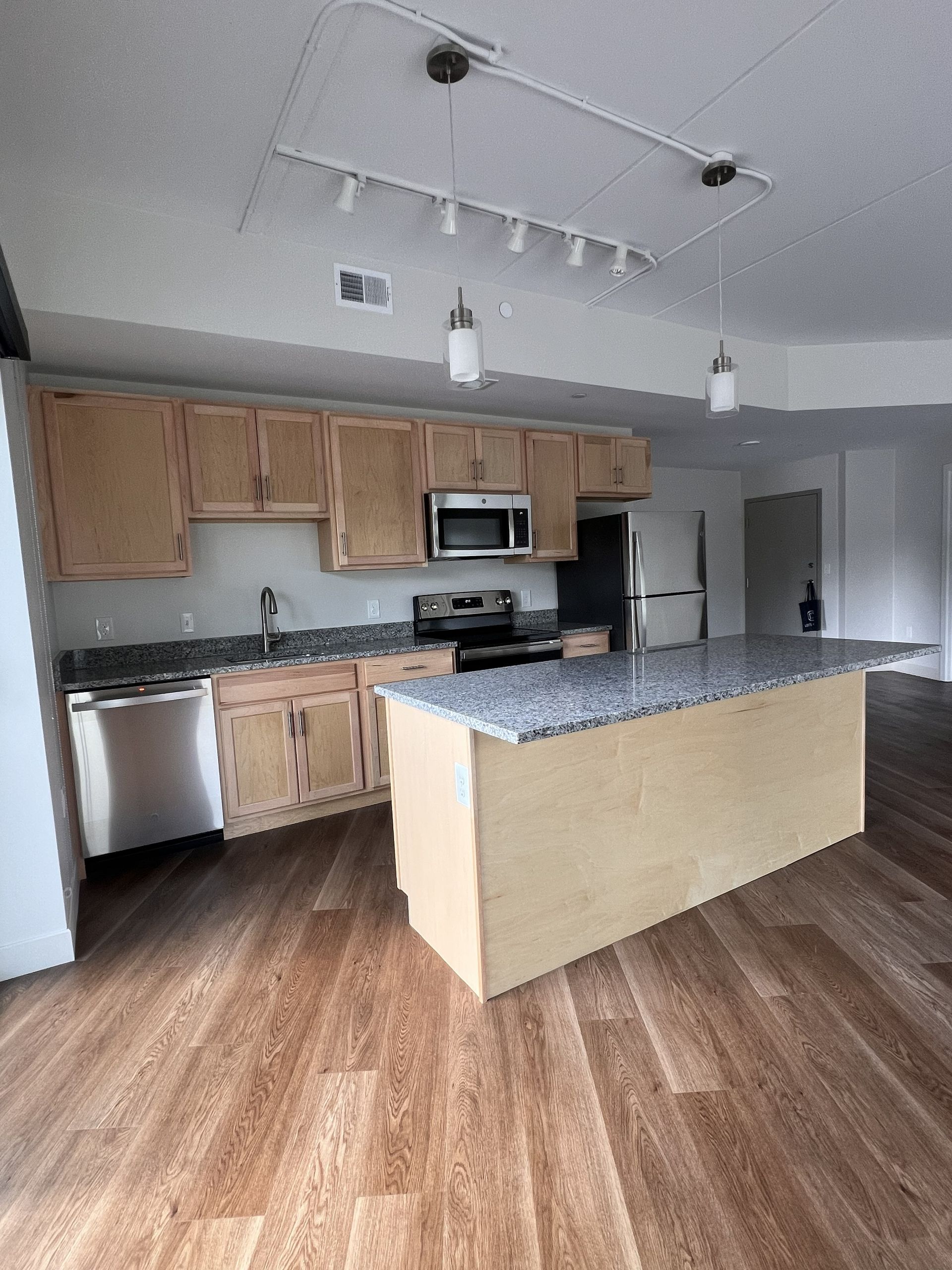 Bright kitchen with wood cabinets, stainless appliances, granite island, and hardwood floors