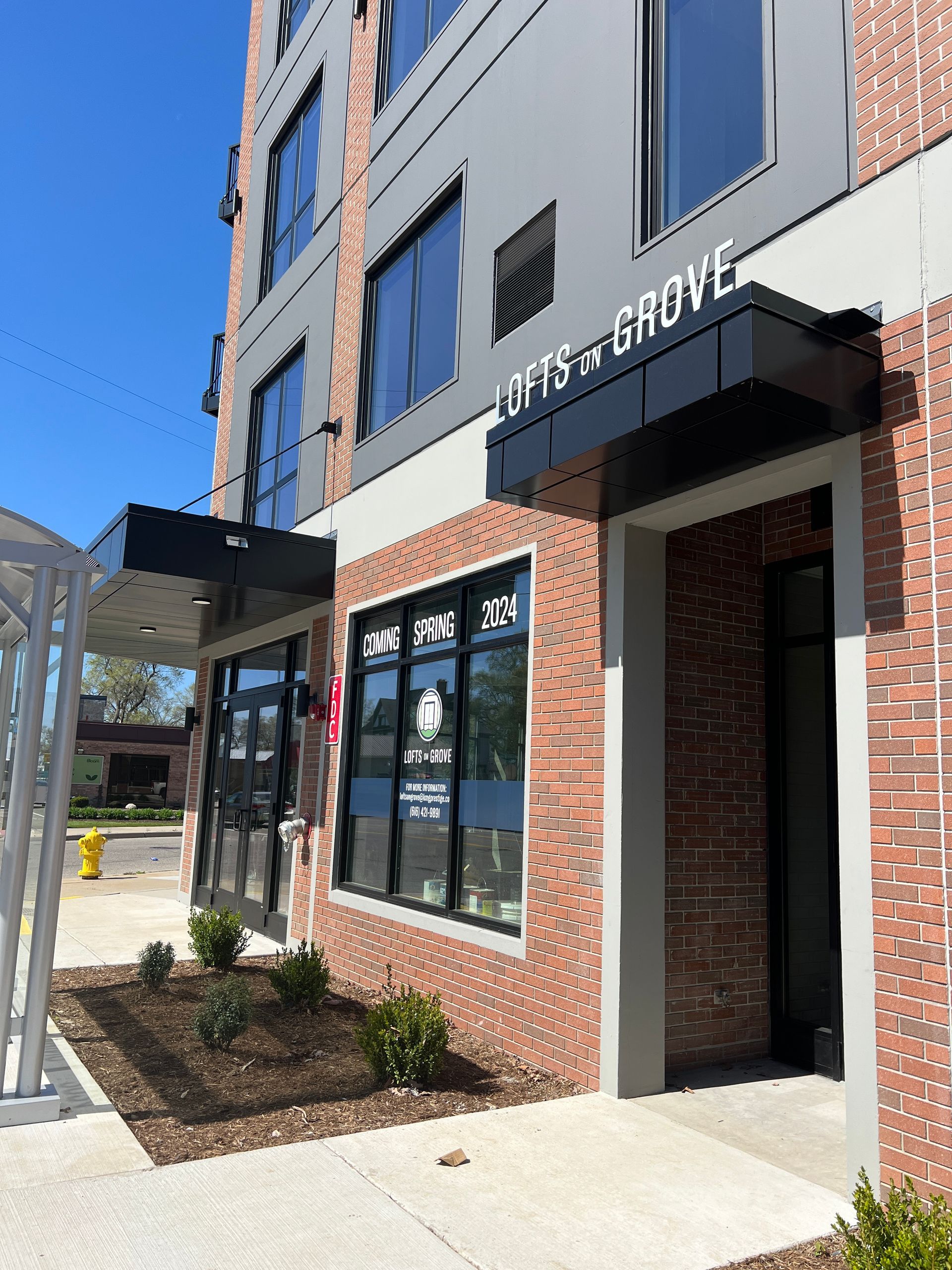 Storefront entrance with brick and gray facade, large windows, and a covered walkway outside.