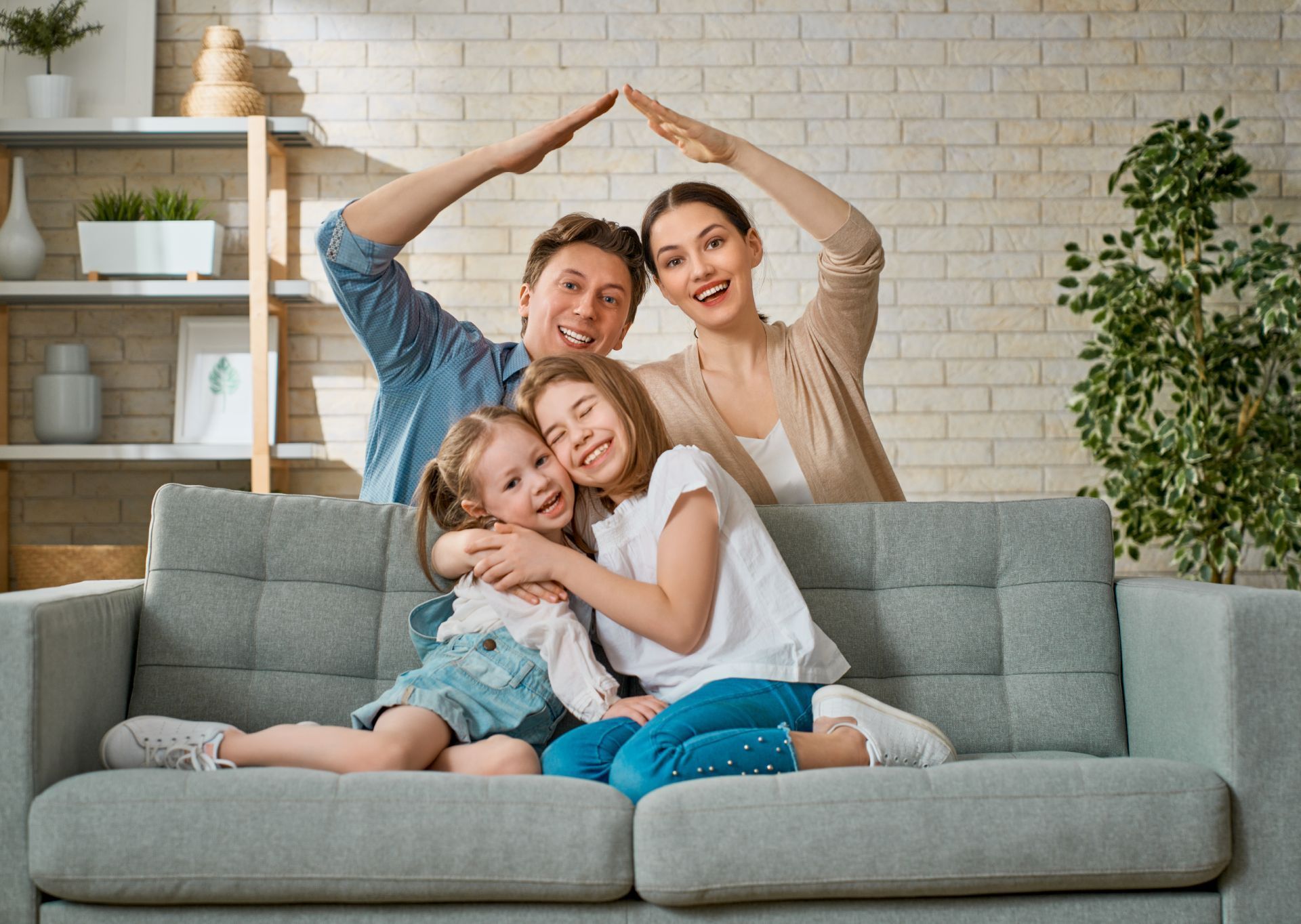 Family smiling and posing together on a gray couch in a bright living room